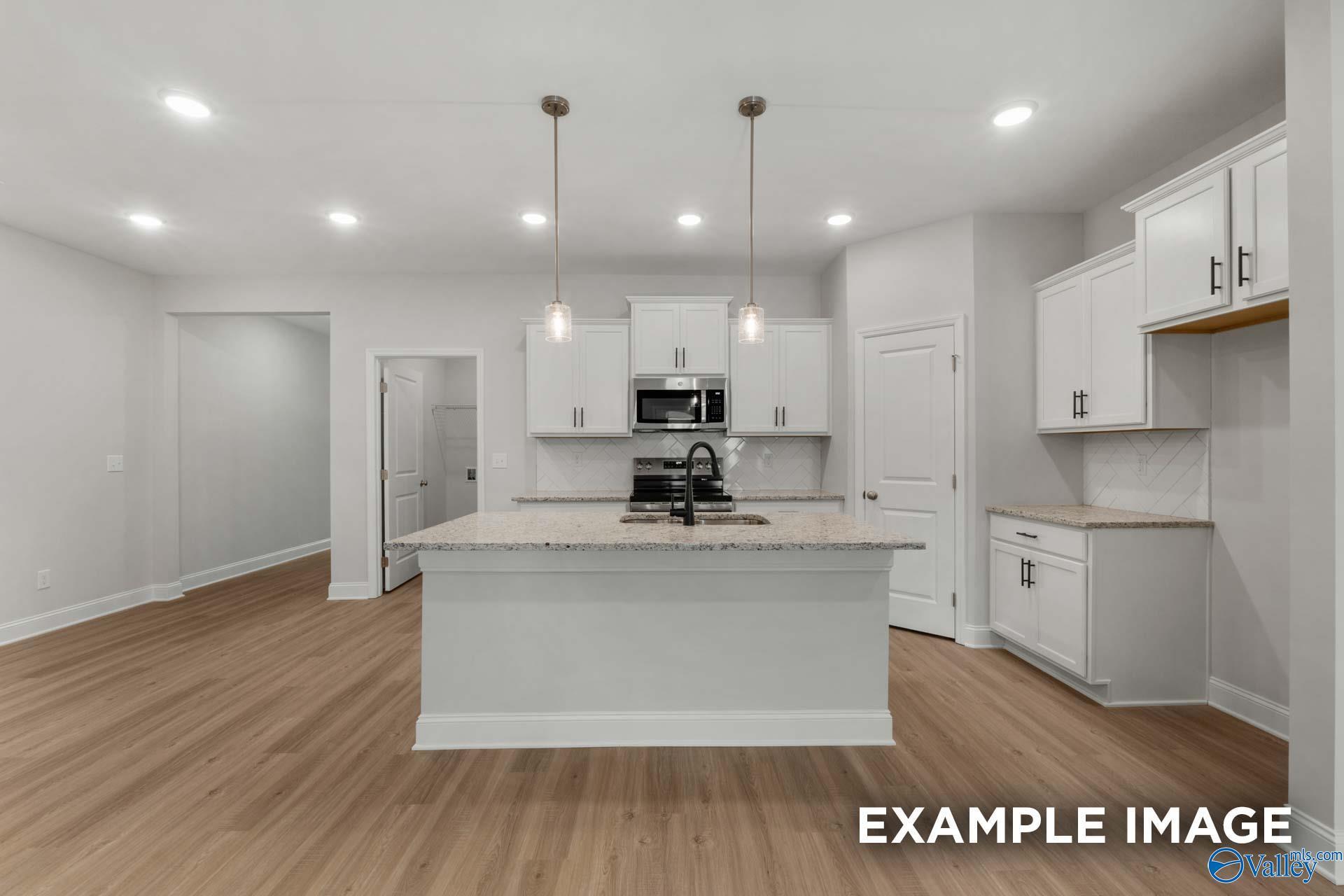 Modern open-concept kitchen featuring white shaker cabinets, quartz island, stainless steel appliances in The Camilla C by Davidson Homes, Hartselle, AL