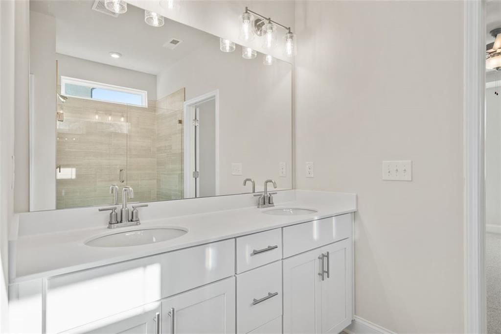 Modern master bathroom featuring double white vanity, frameless glass shower with subway tile in Davidson Homes The Ash C at Wehunt Meadows, Hoschton
