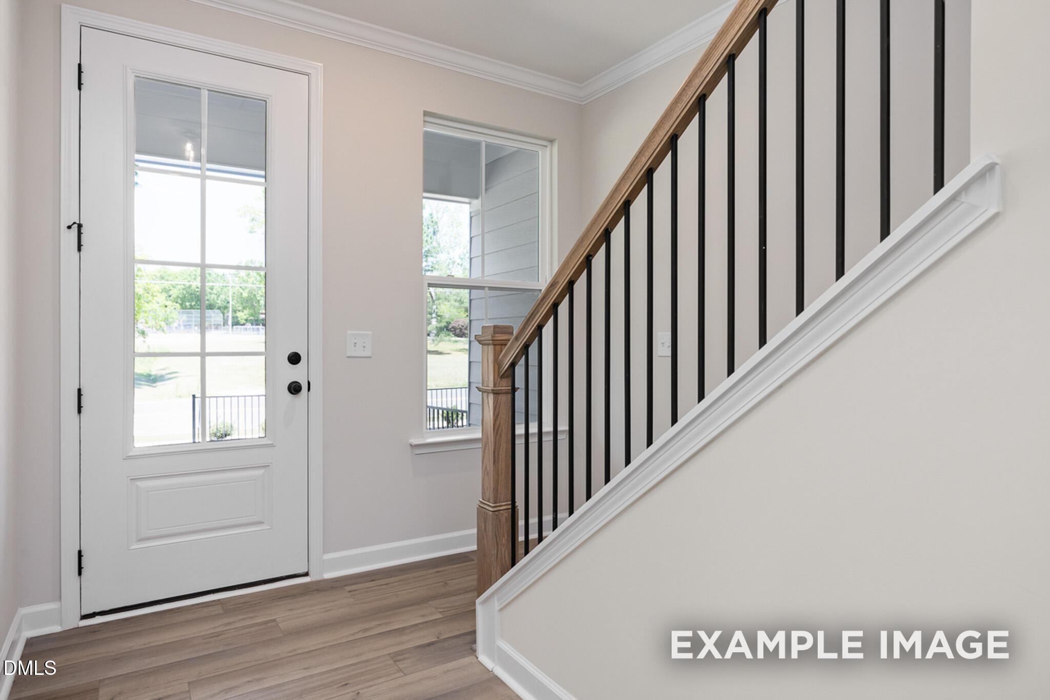 Bright entryway with modern staircase and wooden handrail in The Mitchell floor plan at Camden Park, Knightdale, NC.
