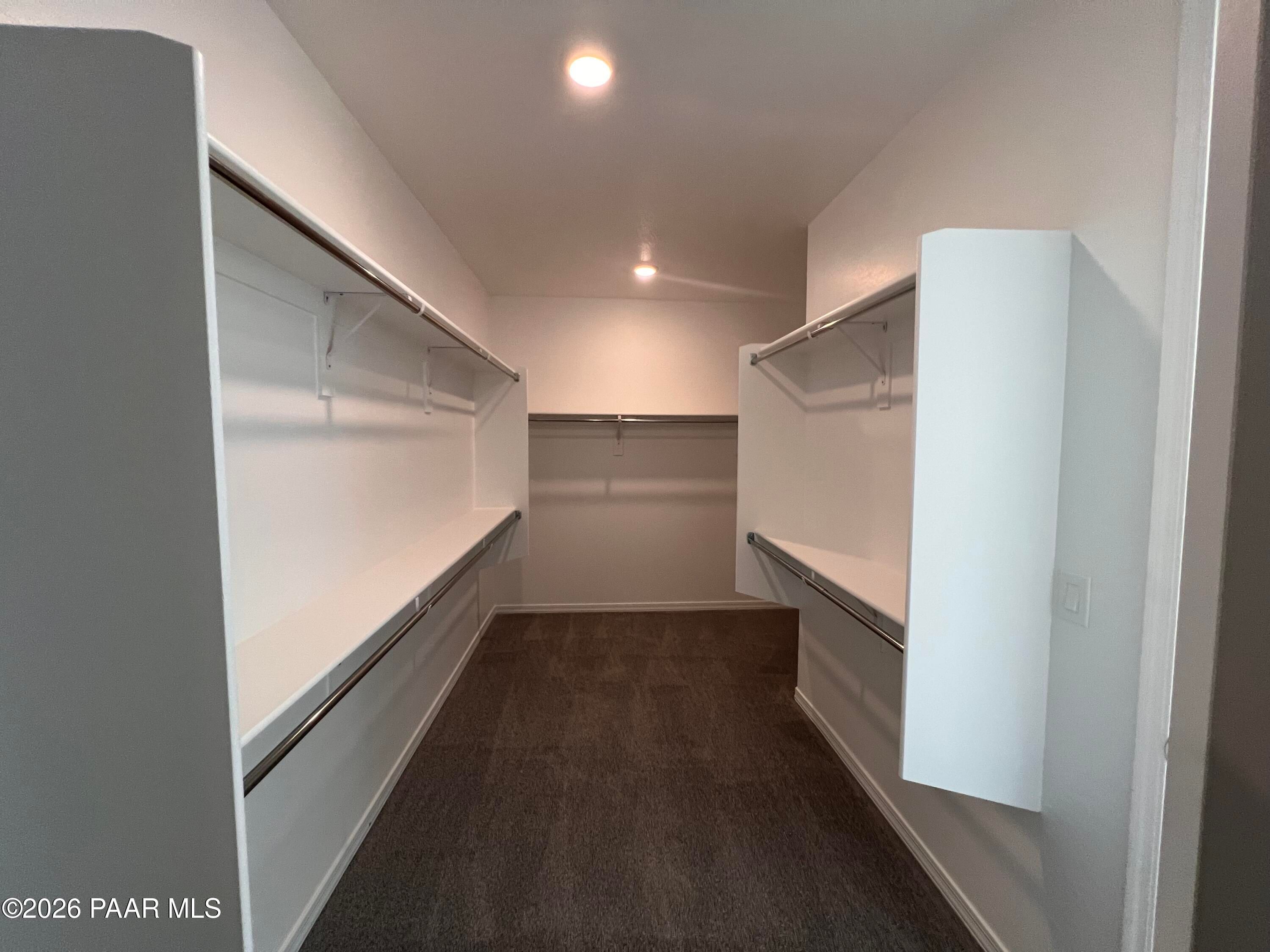 Spacious walk-in closet with dual hanging rods, built-in shelves, and gray carpet in Davidson Homes The Sunrise II A, Prescott, Arizona