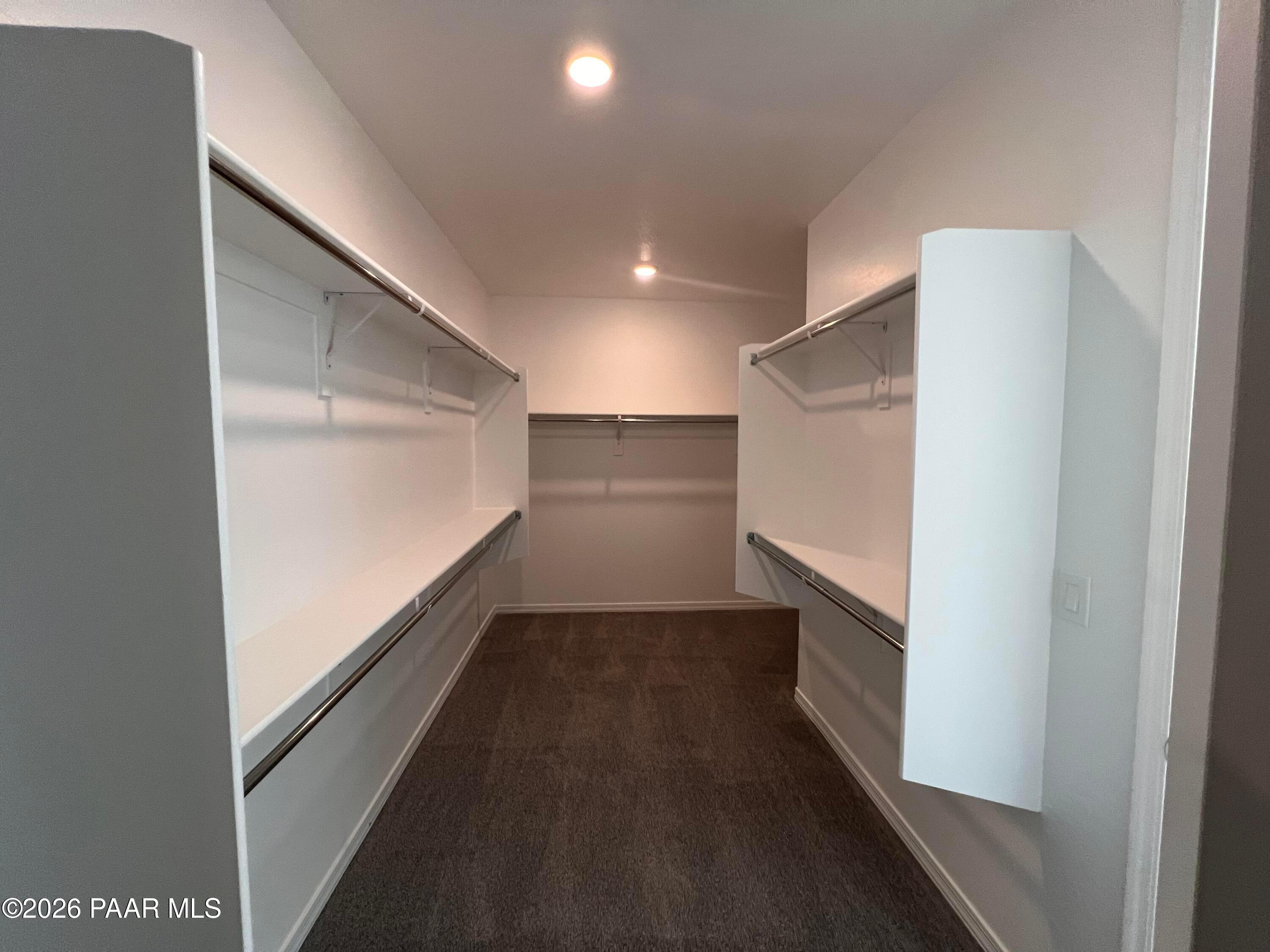 Spacious walk-in closet with dual hanging rods, built-in shelves, and gray carpet in Davidson Homes The Sunrise II A, Prescott, Arizona