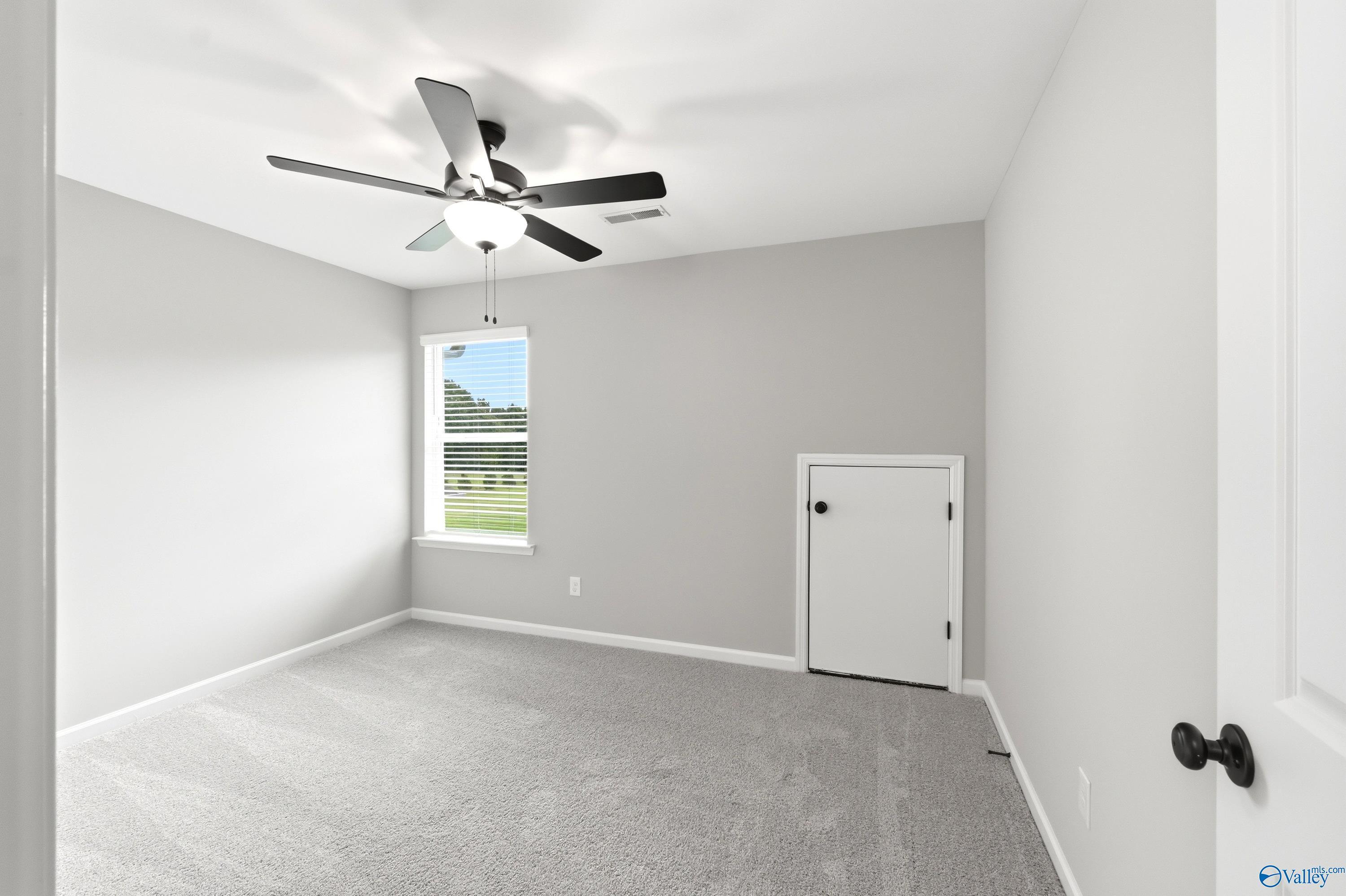 Spacious bedroom with grey carpet, ceiling fan, and attic storage access in The Dorado floor plan at Riverton Preserve.