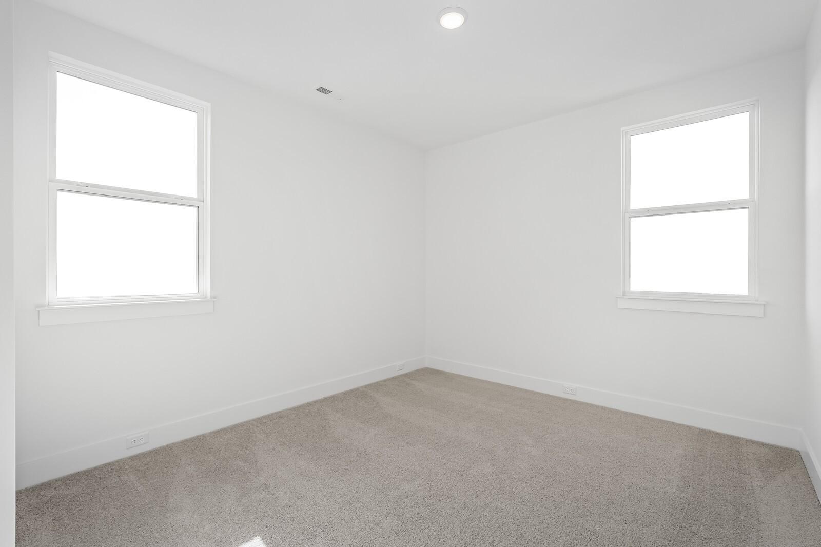 Bright empty bedroom with double-hung windows and neutral carpet in The Alston A, Shelton Square, Murfreesboro TN