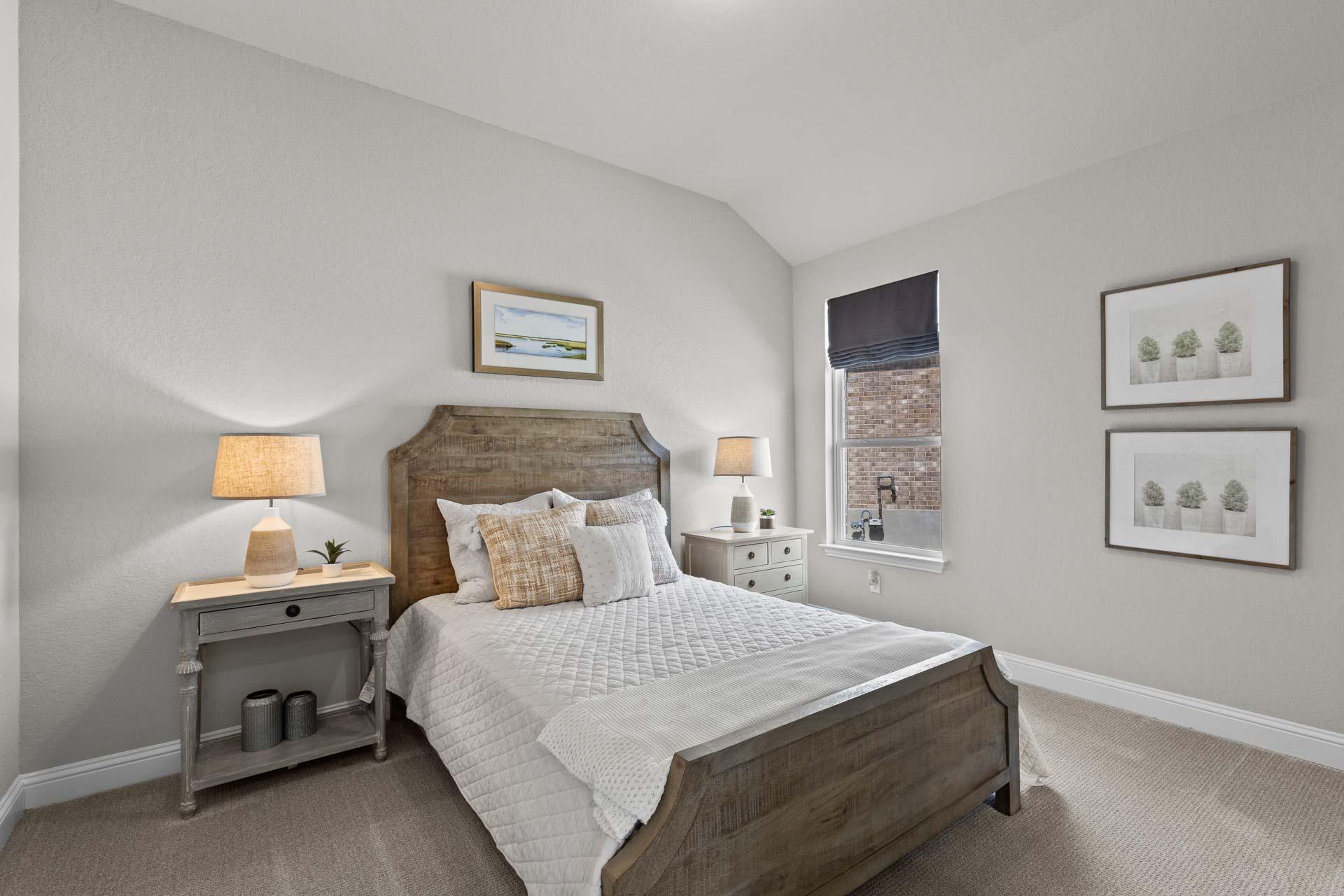 Cozy secondary bedroom in The Garner A Davidson Homes design with wooden bed frame, neutral gray walls, and artwork