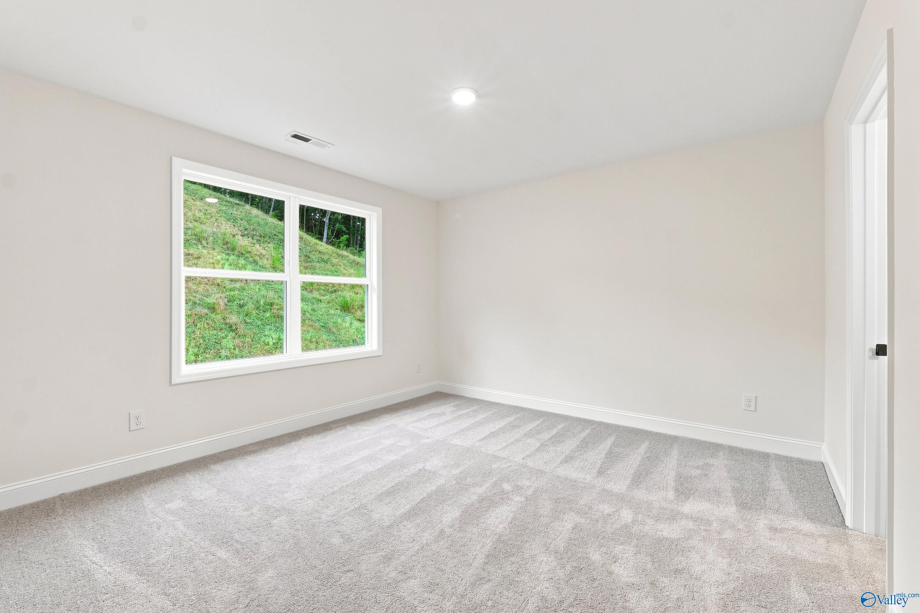 Bright, carpeted bedroom with large window in The Shelby D floor plan at Noble Ridge, Cullman, Alabama.