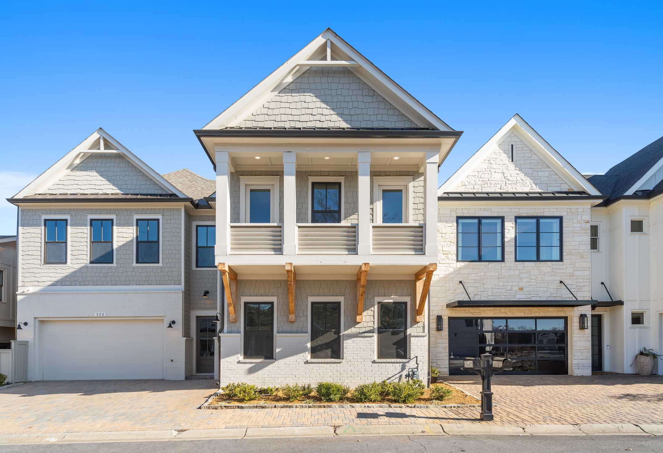 Modern two-story Seaside home by Davidson Homes in Woodstock GA with white siding, shake roof, balcony, and three-car garage