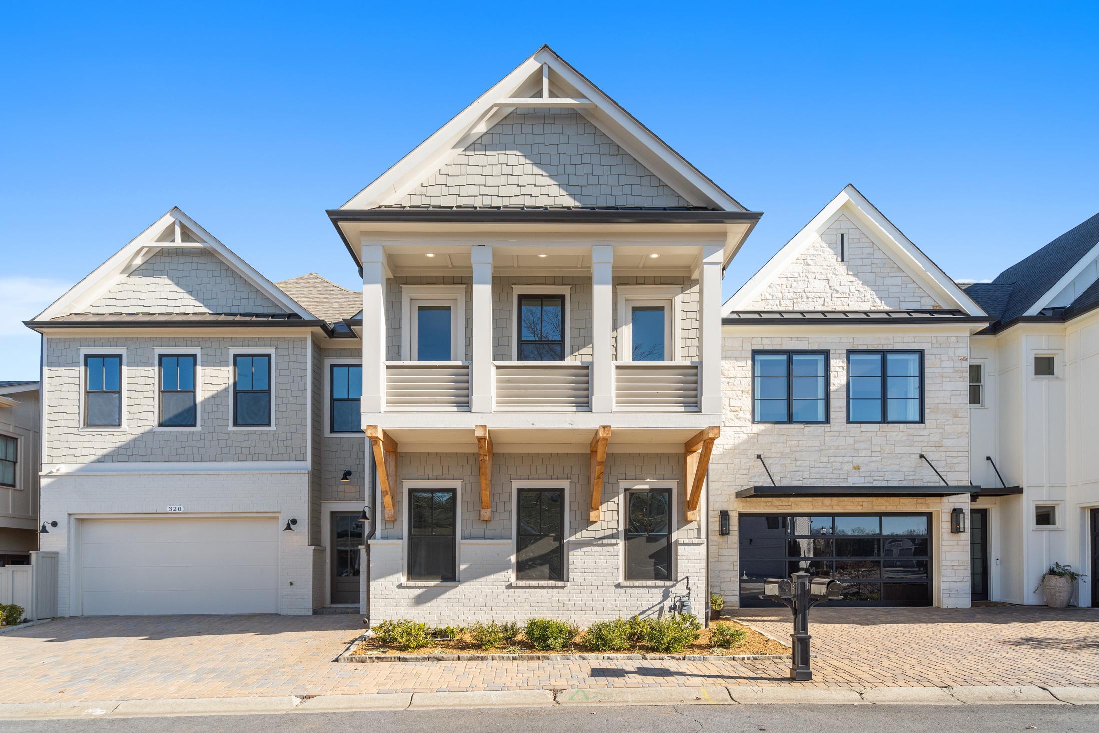 Modern two-story Seaside home by Davidson Homes in Woodstock GA with white siding, shake roof, balcony, and three-car garage