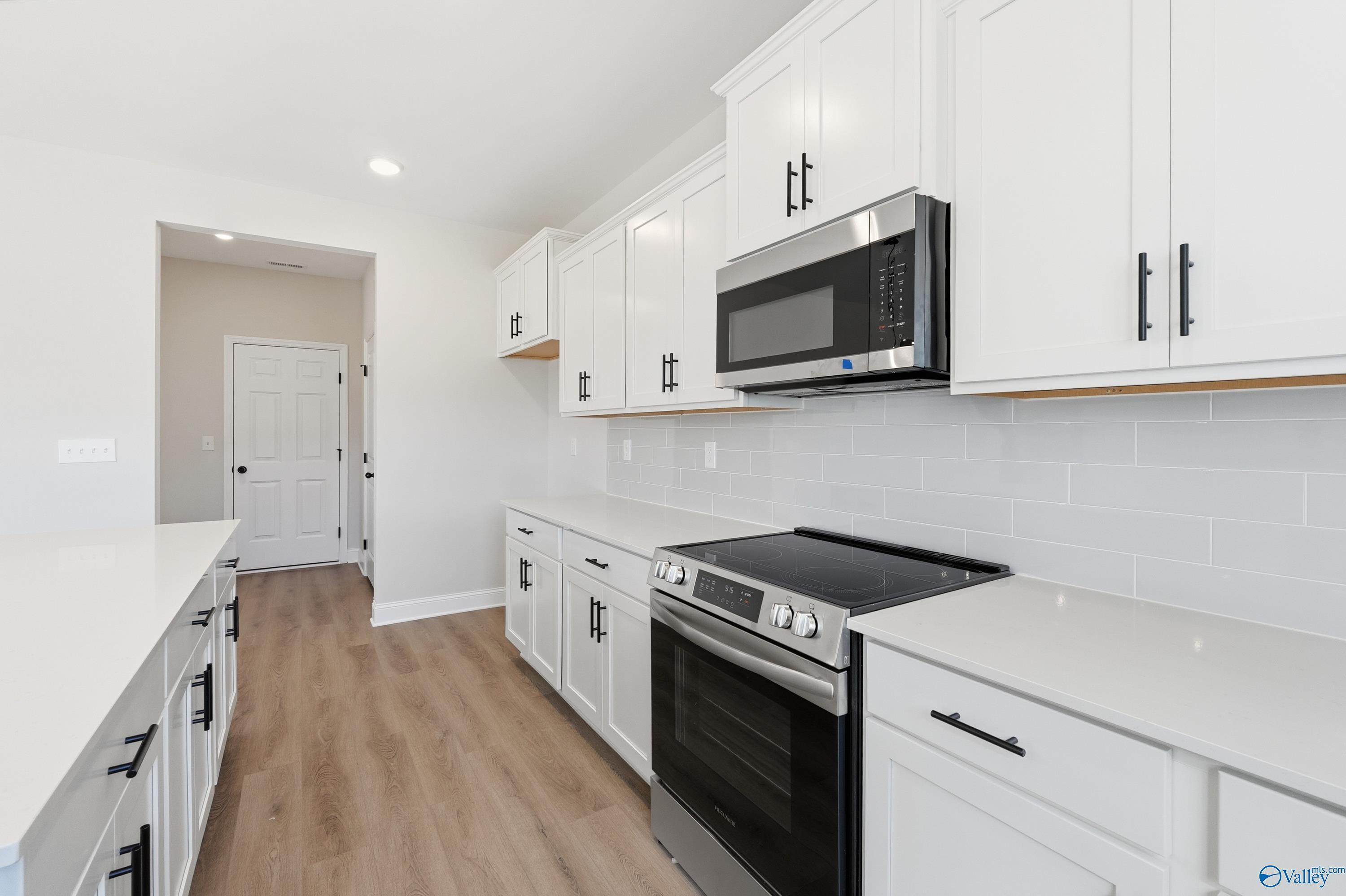 Modern white kitchen with stainless steel appliances, subway tile backsplash, and quartz island in Davidson Homes The Chelsea C, Harvest AL