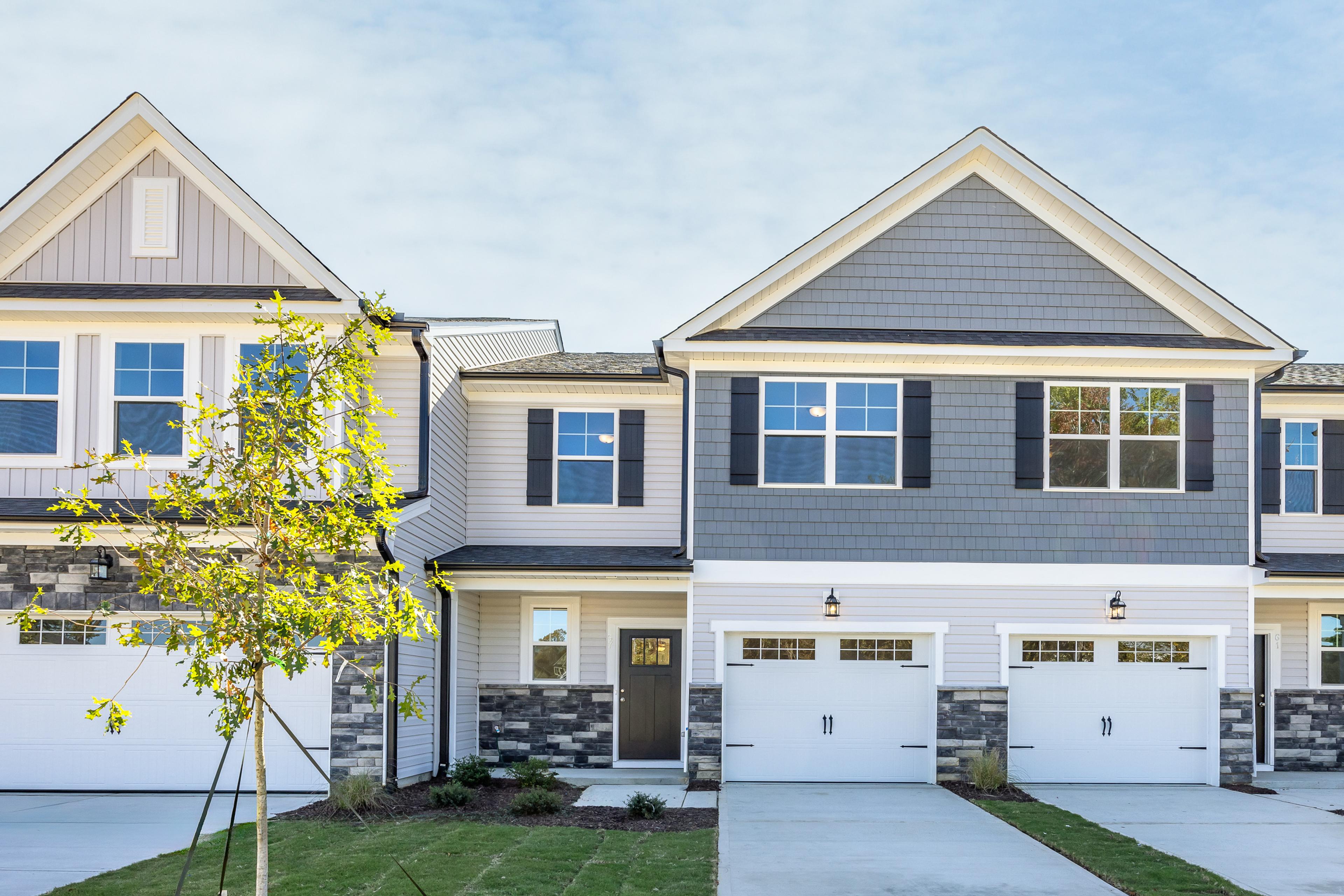 Modern townhome exterior at Gregory Village in Lillington, NC, featuring stone accents, gray siding, and attached garages.