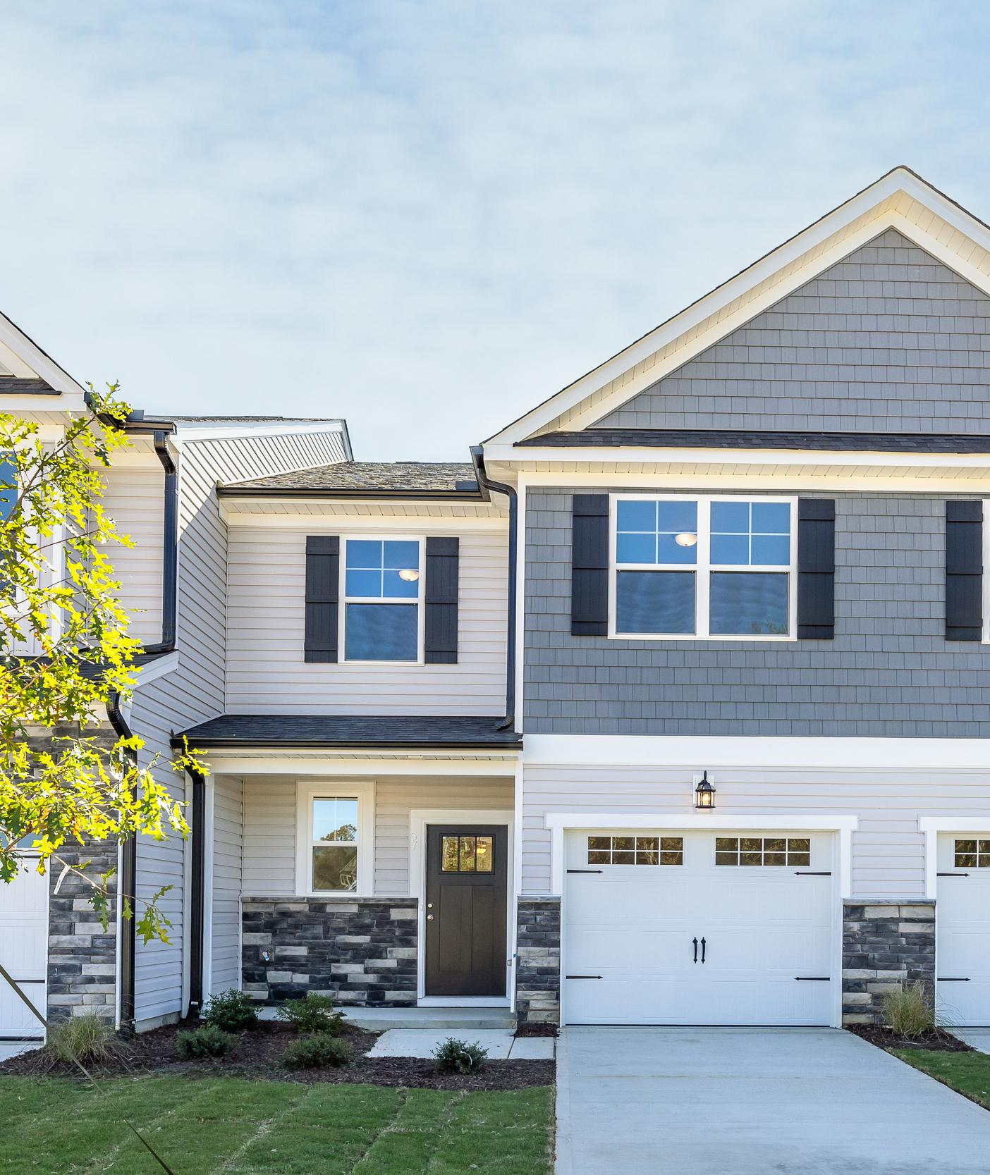 Modern townhome exterior at Gregory Village in Lillington, NC, featuring stone accents, gray siding, and attached garages.