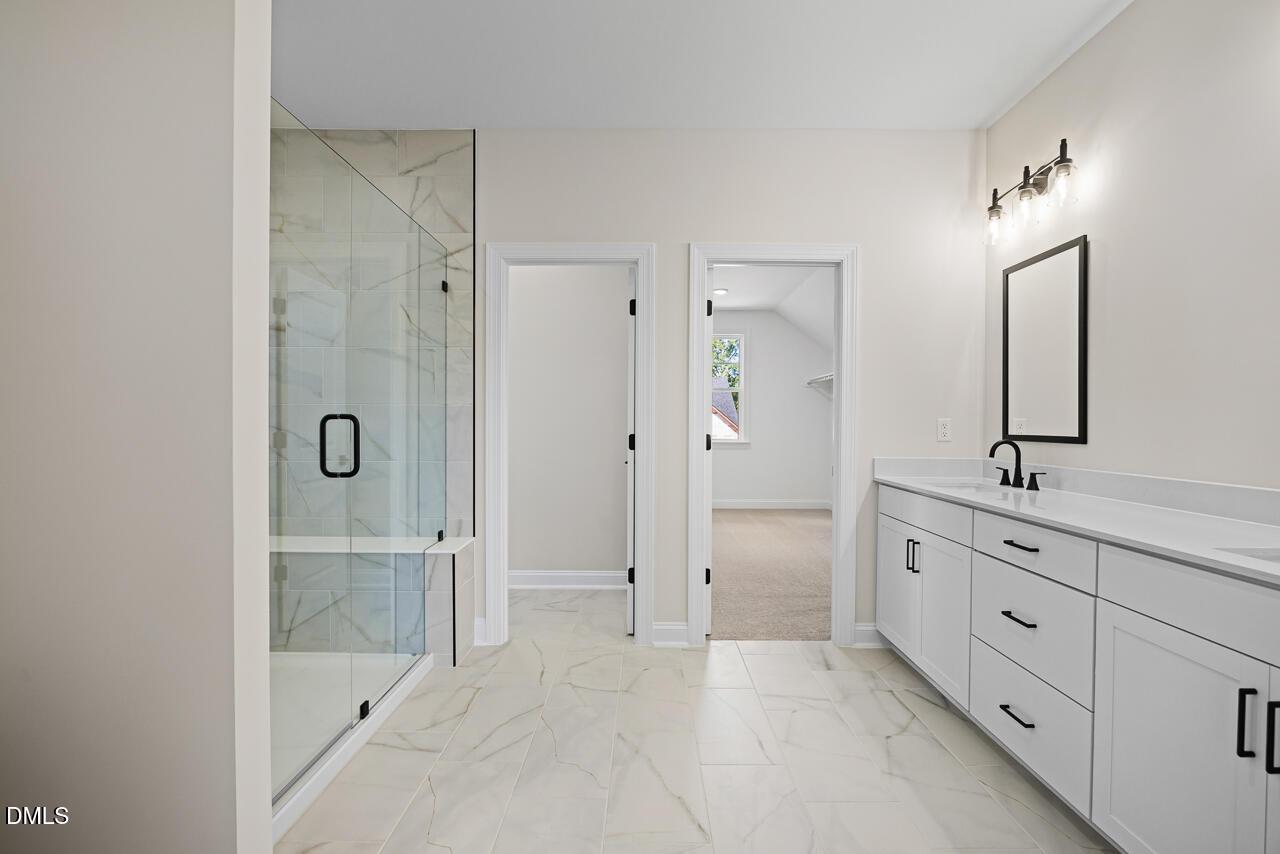 Modern master bathroom with glass walk-in shower, white vanity, and marble tile flooring in The Crawford D plan, Wake Forest, NC
