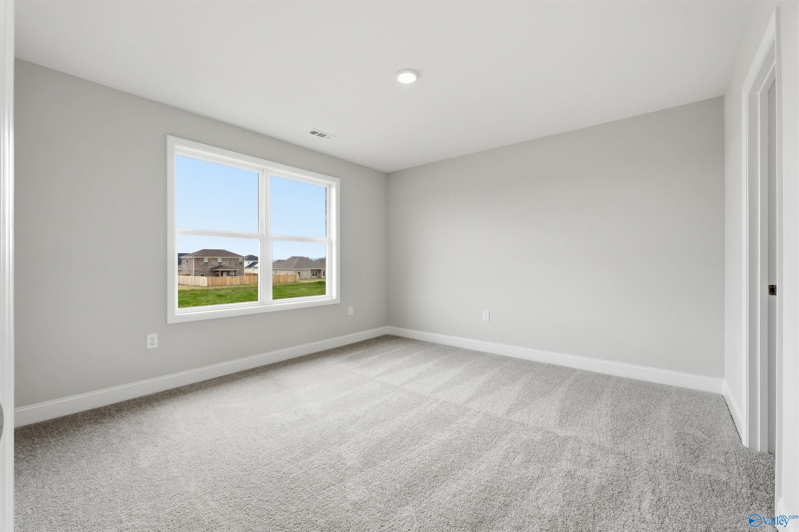 Bright, carpeted bedroom with neutral walls in The Shelby D floor plan at Evergreen Mill, Madison, Alabama.