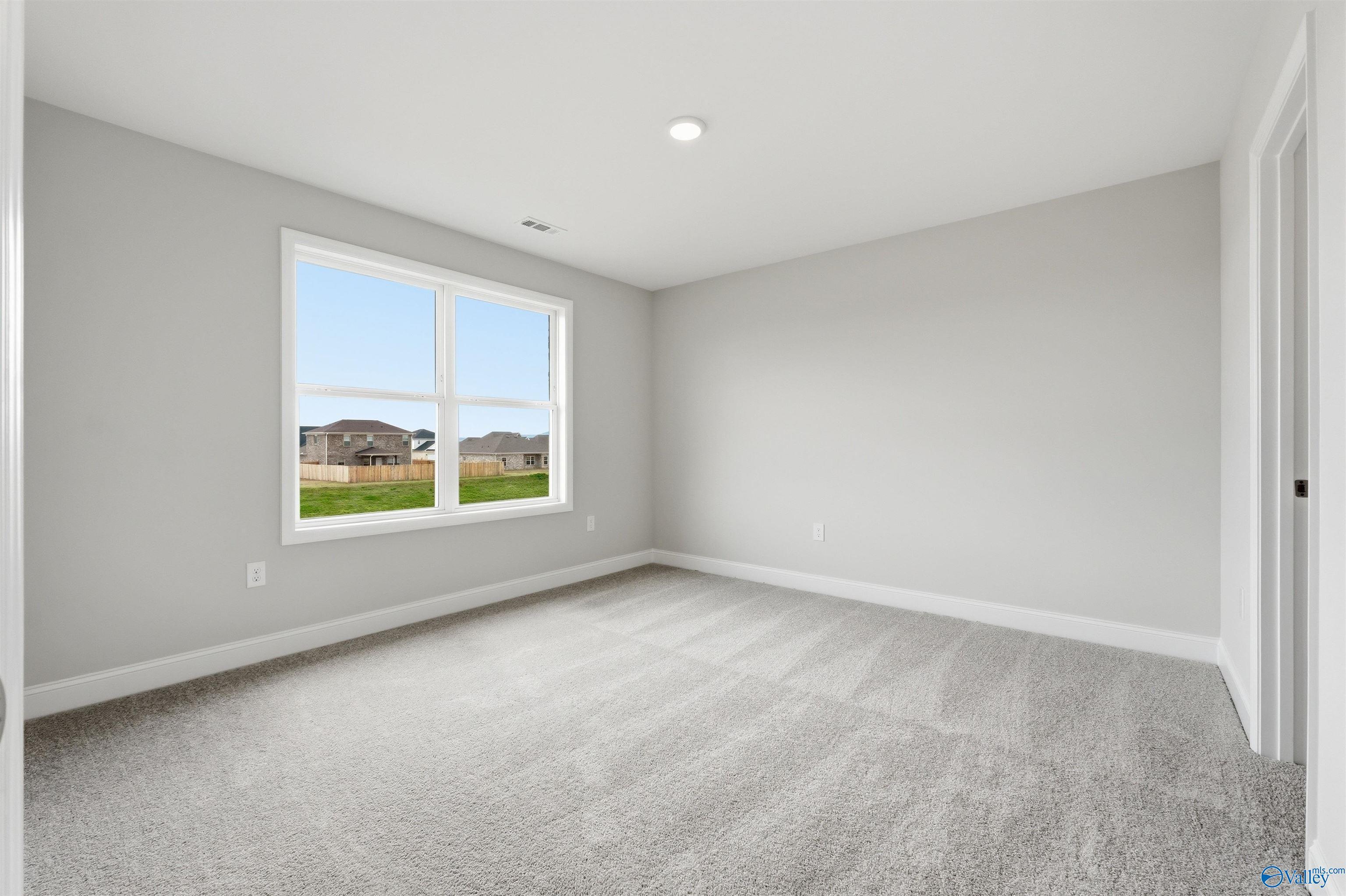 Bright, carpeted bedroom with neutral walls in The Shelby D floor plan at Evergreen Mill, Madison, Alabama.