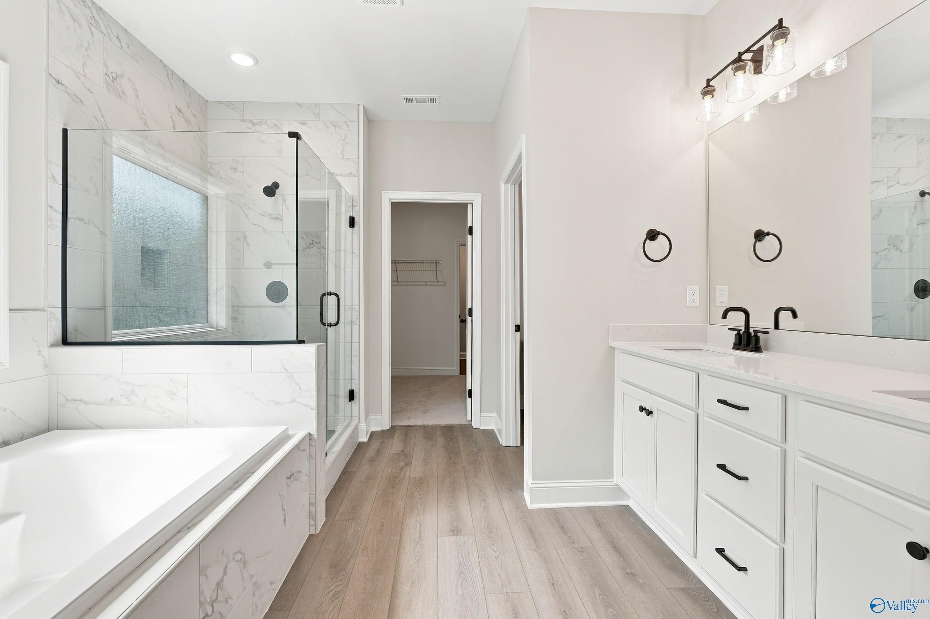 Modern master bathroom with soaking tub, glass shower, and double vanity in a Davidson Homes Rockford B floor plan in Toney.