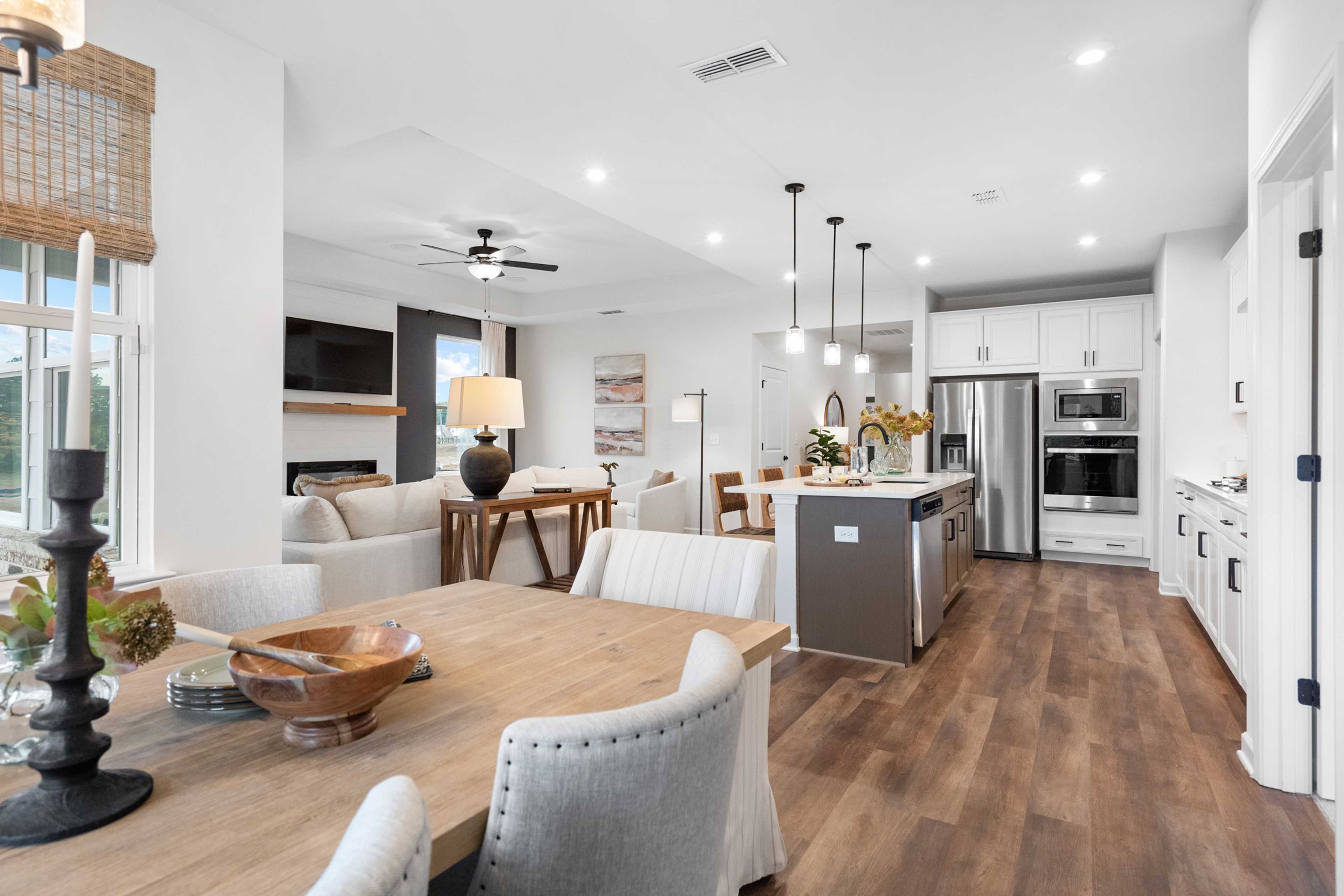 Open-concept kitchen and living room at Kelly Preserve in Loganville GA with hardwood floors white island fireplace and dining area