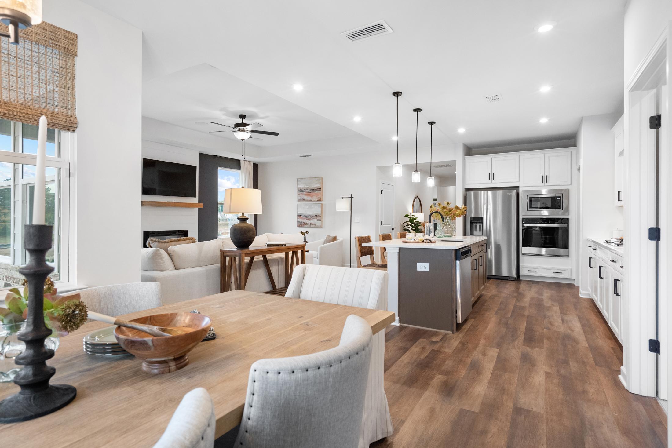 Open-concept kitchen and living room at Kelly Preserve in Loganville GA with hardwood floors white island fireplace and dining area