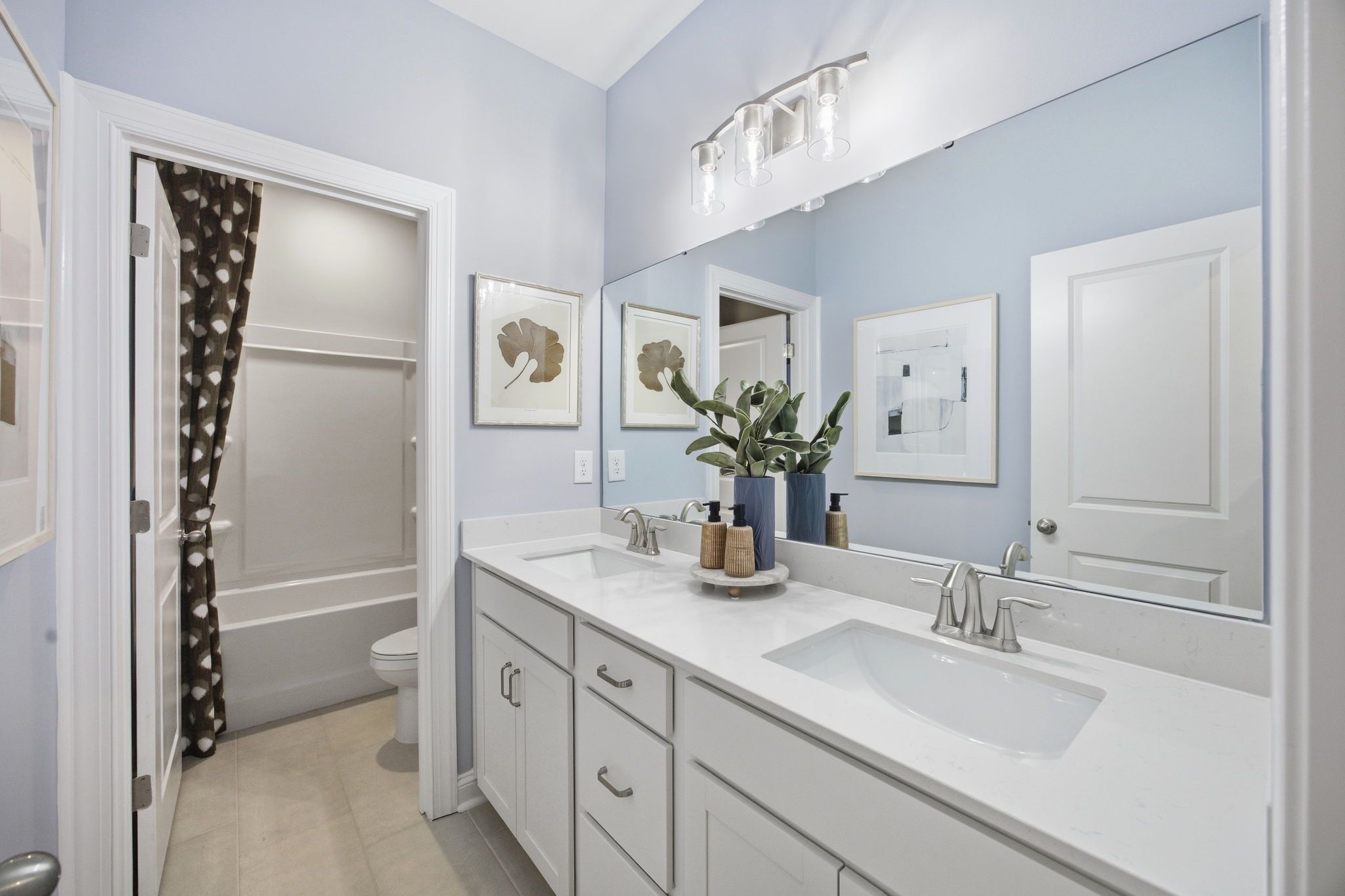 Spacious modern bathroom at Enclave at Belmont in Belmont NC with light blue walls, double quartz vanity, bathtub