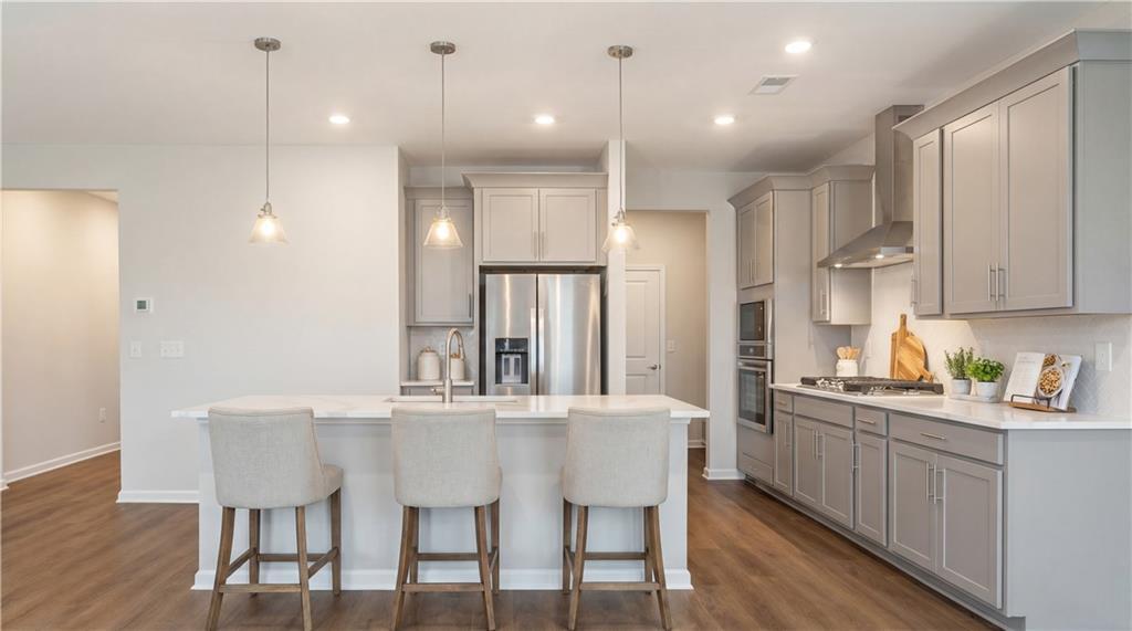 Modern kitchen with white shaker cabinets, stainless steel appliances, quartz island and bar stools in Davidson Homes The Marion A, Winder, GA