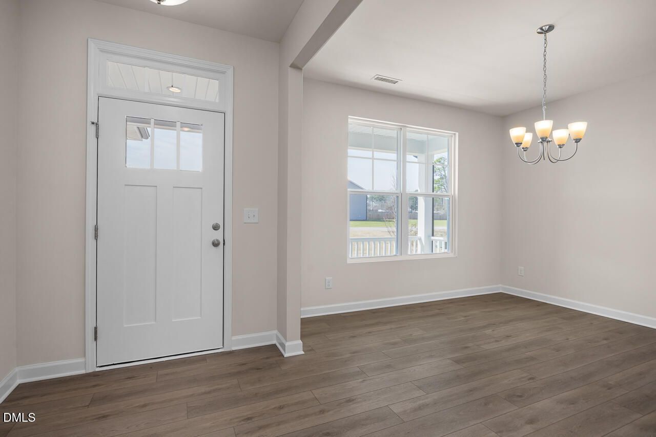 Bright entry foyer with white glass-paneled door, hardwood floors, and chandelier in Davidson Homes The Ash B, Lillington, NC
