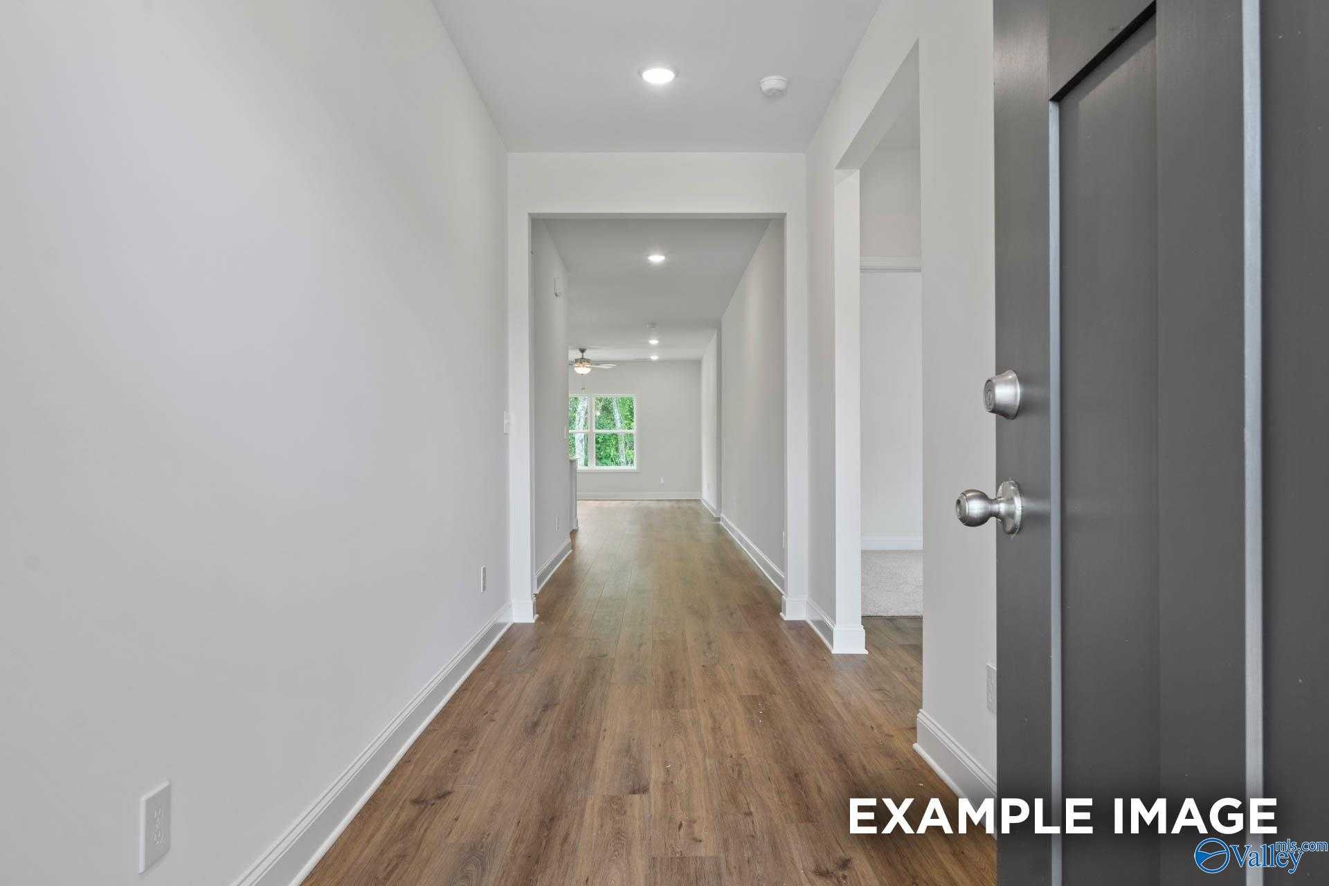 Bright hallway with light wood floors, white walls, and recessed lights in Davidson Homes The Daphne D, Athens, Alabama