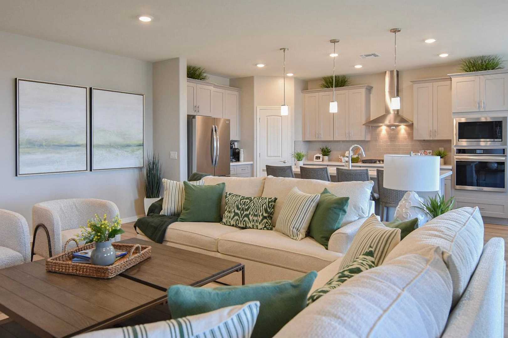 Open-concept kitchen and living room at North Ridge Pronghorn Ranch in Prescott Valley AZ with white cabinetry, stainless appliances, island, and plush beige sofa