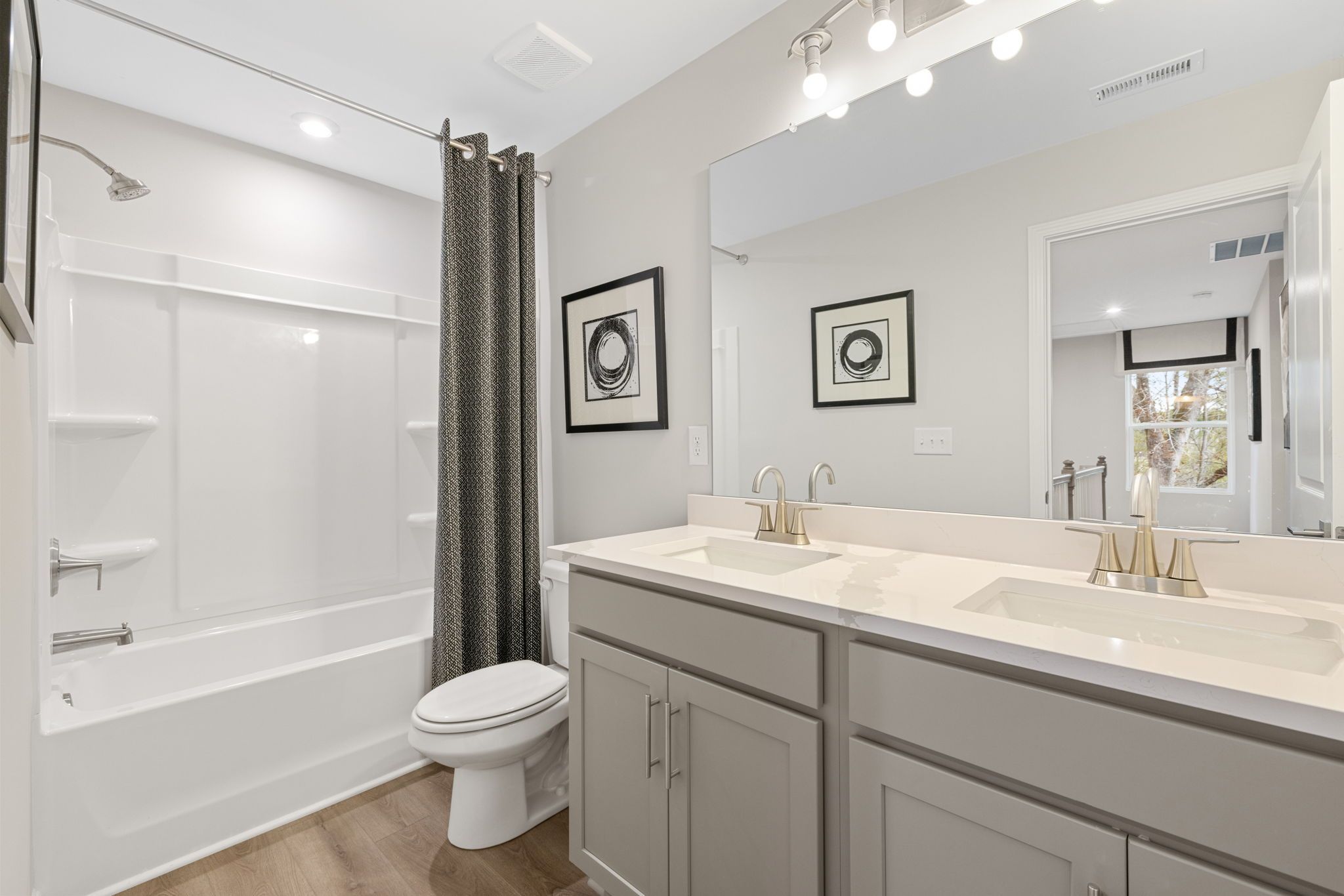 Modern bathroom at Lake Shore in Winder, Georgia with double vanity, tub-shower combo, and gray cabinetry