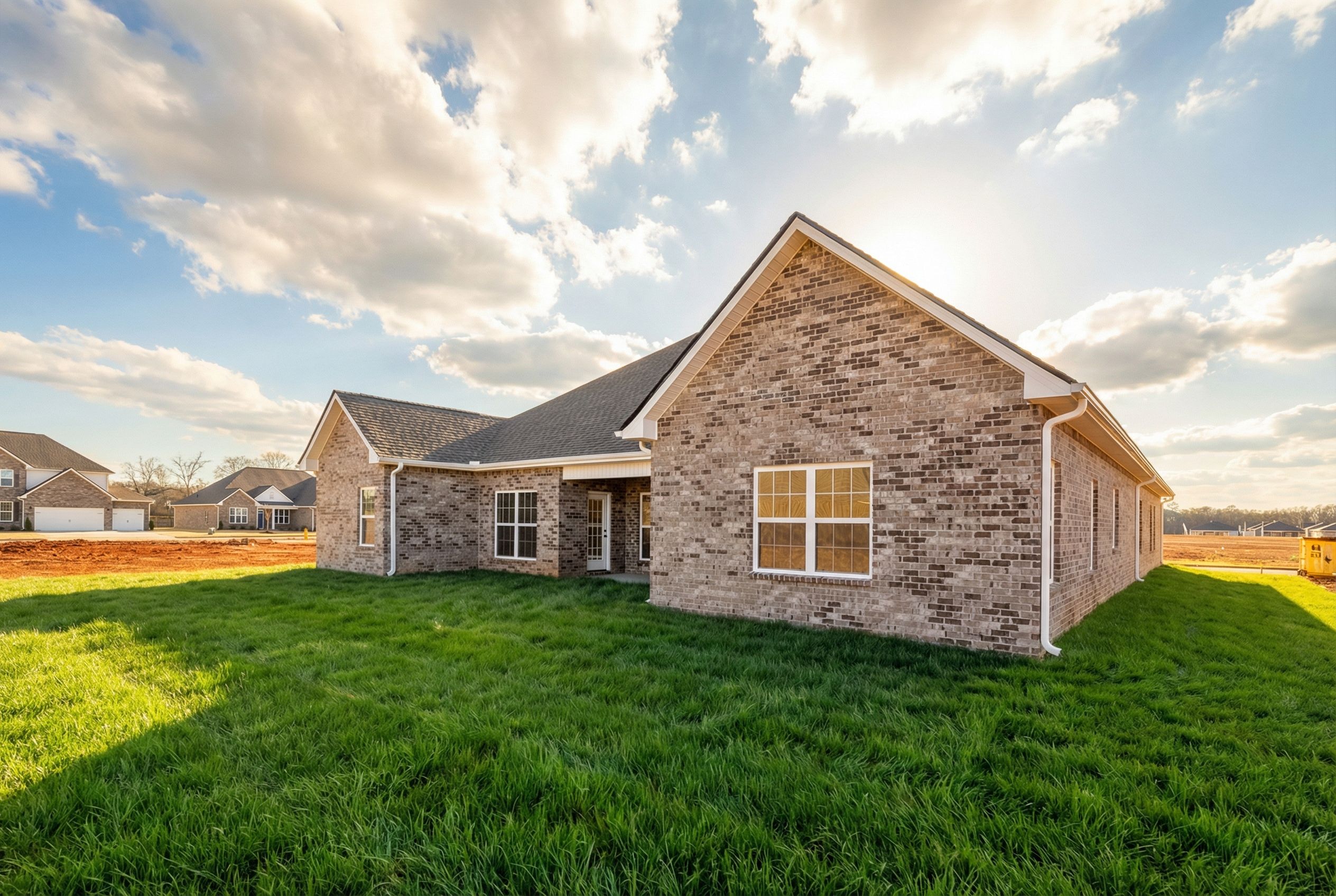 Single-story brick Valencia home elevation with 3-car garage, large windows, and lush green lawn in sunny Meridianville Alabama