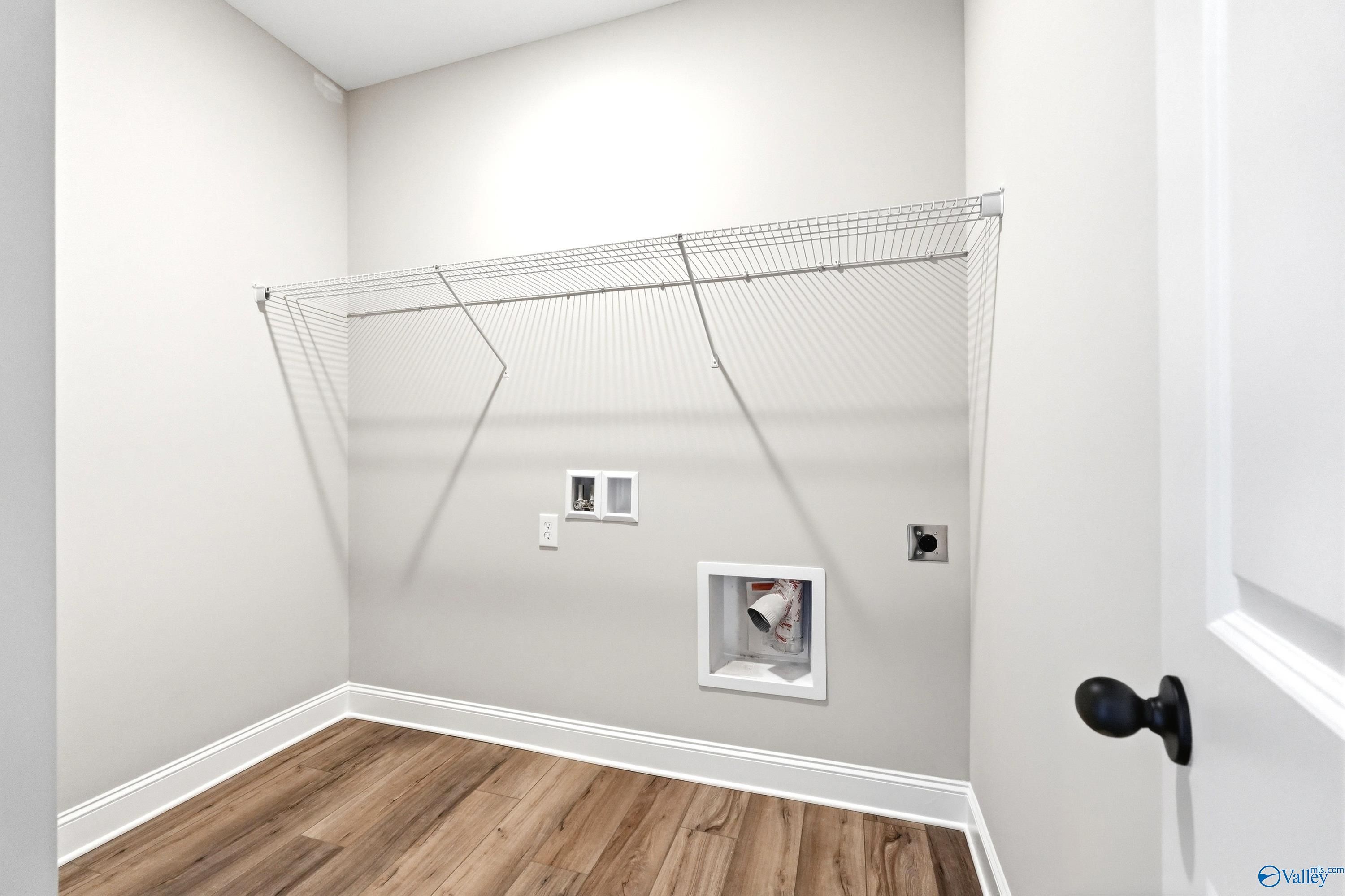 Laundry room with wire shelving and utility hookups in The Daphne D floor plan by Davidson Homes in Harvest, Alabama.