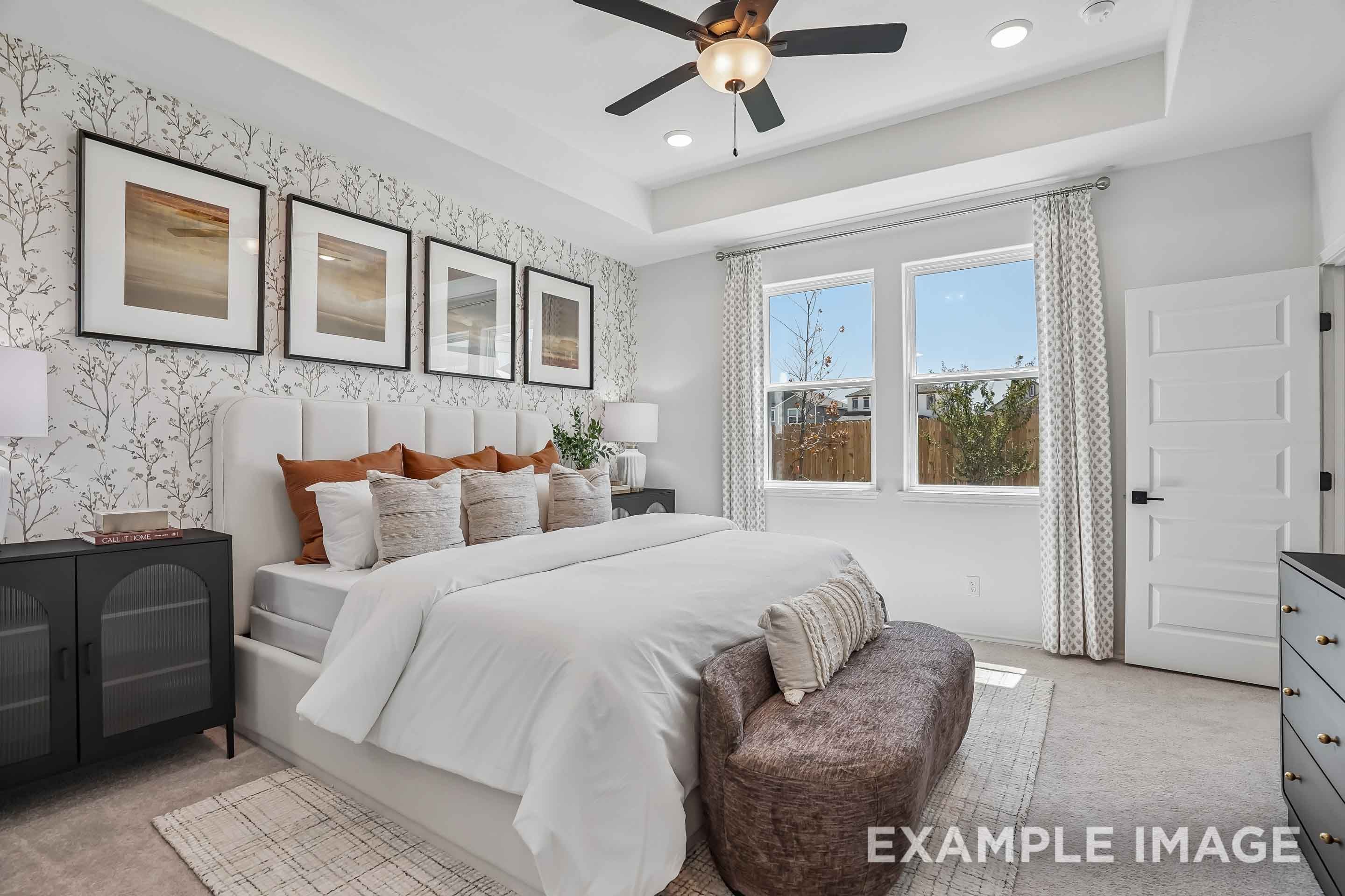 Spacious master suite in The Pinecrest featuring a tray ceiling, designer wallpaper, and plush bedding in San Antonio, Texas.