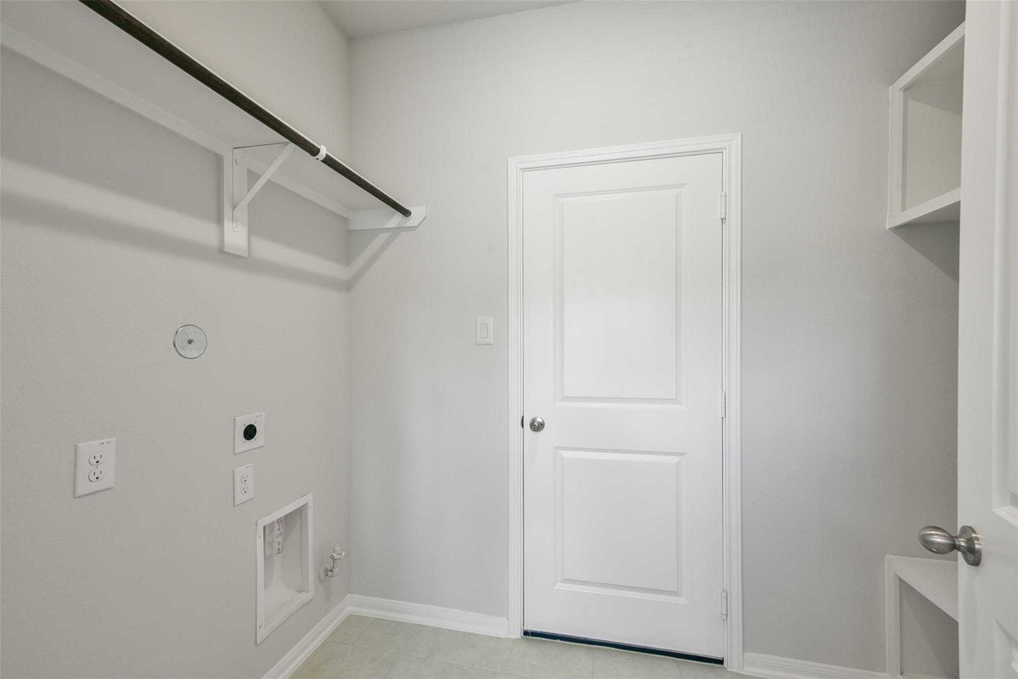 Functional laundry room with washer dryer hookups, hanging rod, and storage cabinets in Davidson Homes The Sabine E, Dayton Texas