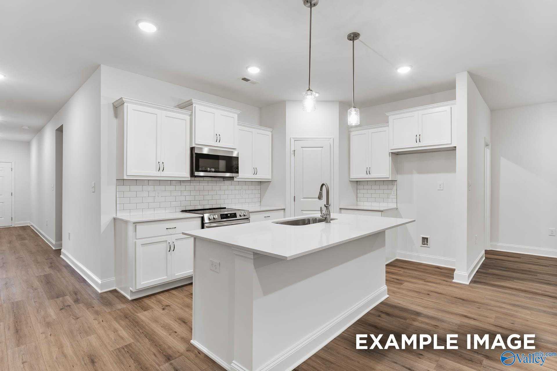 Modern white kitchen with island, stainless appliances, subway tile backsplash in The Daphne 4-bedroom home, New Market, Alabama
