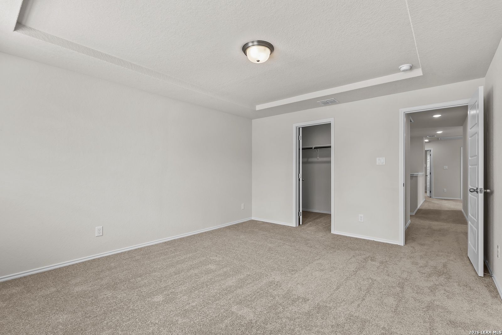 Spacious bedroom with tray ceiling and walk-in closet in The Gillian B floor plan at Meadows at Oak Creek, San Antonio.