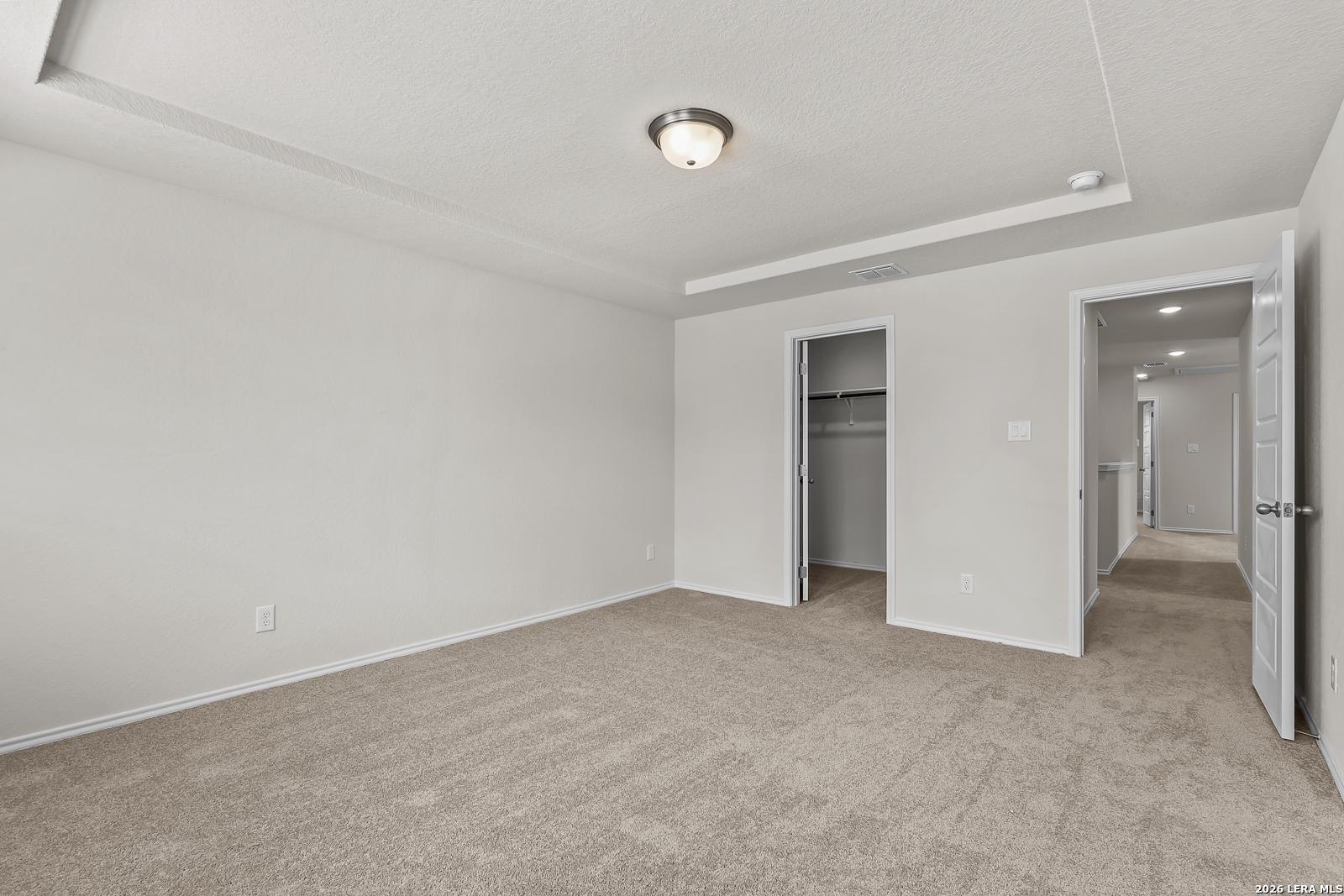 Spacious bedroom with tray ceiling and walk-in closet in The Gillian B floor plan at Meadows at Oak Creek, San Antonio.