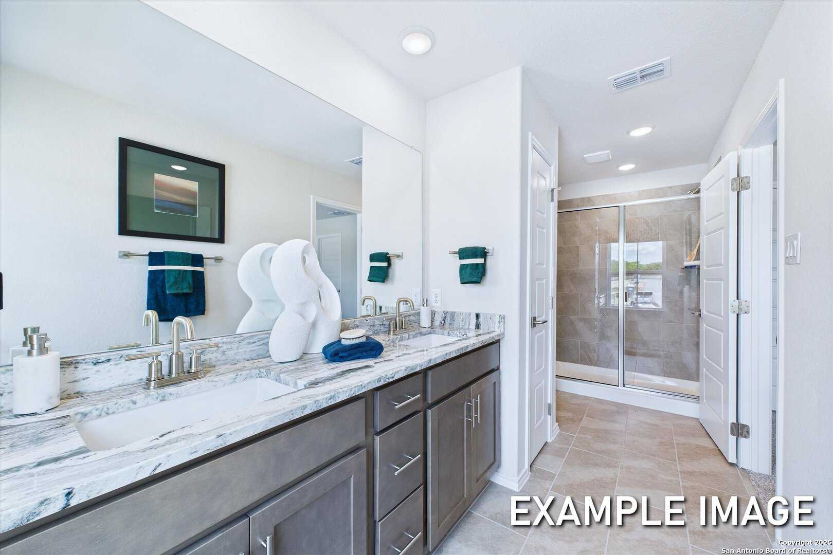 Modern master bathroom with double vanity, gray shaker cabinets, white quartz counters, and glass shower in Davidson Homes The Gillian C, San Antonio