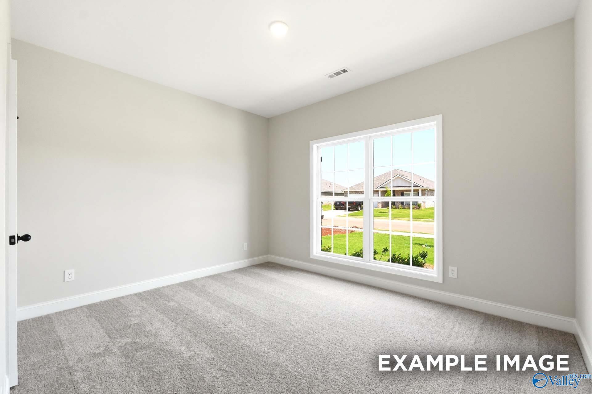 Bright bedroom with neutral carpet in The Daphne floor plan by Davidson Homes at Clearview in Hazel Green, Alabama.