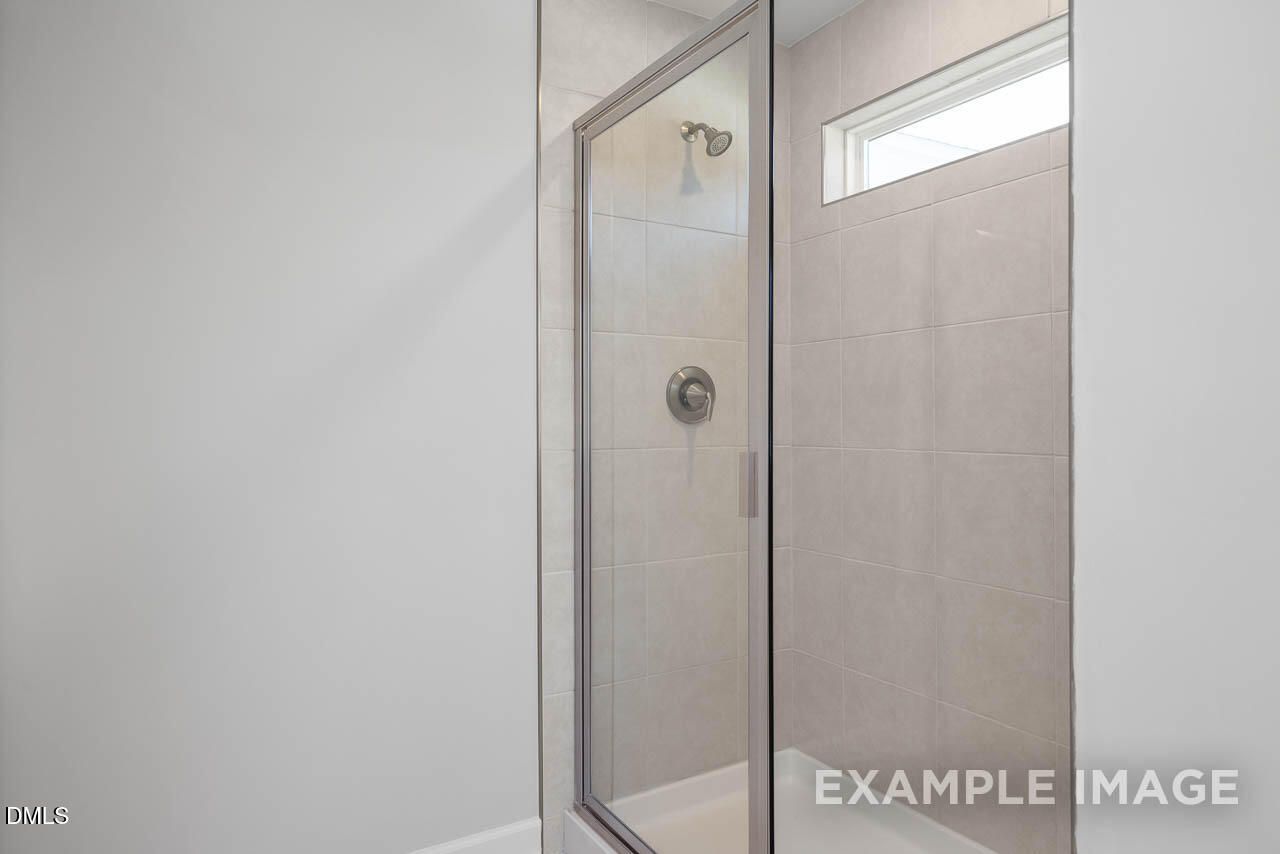 Modern glass shower enclosure with white subway tiles and clerestory window in master bath of Davidson Homes The Adalynn A in Lillington, NC