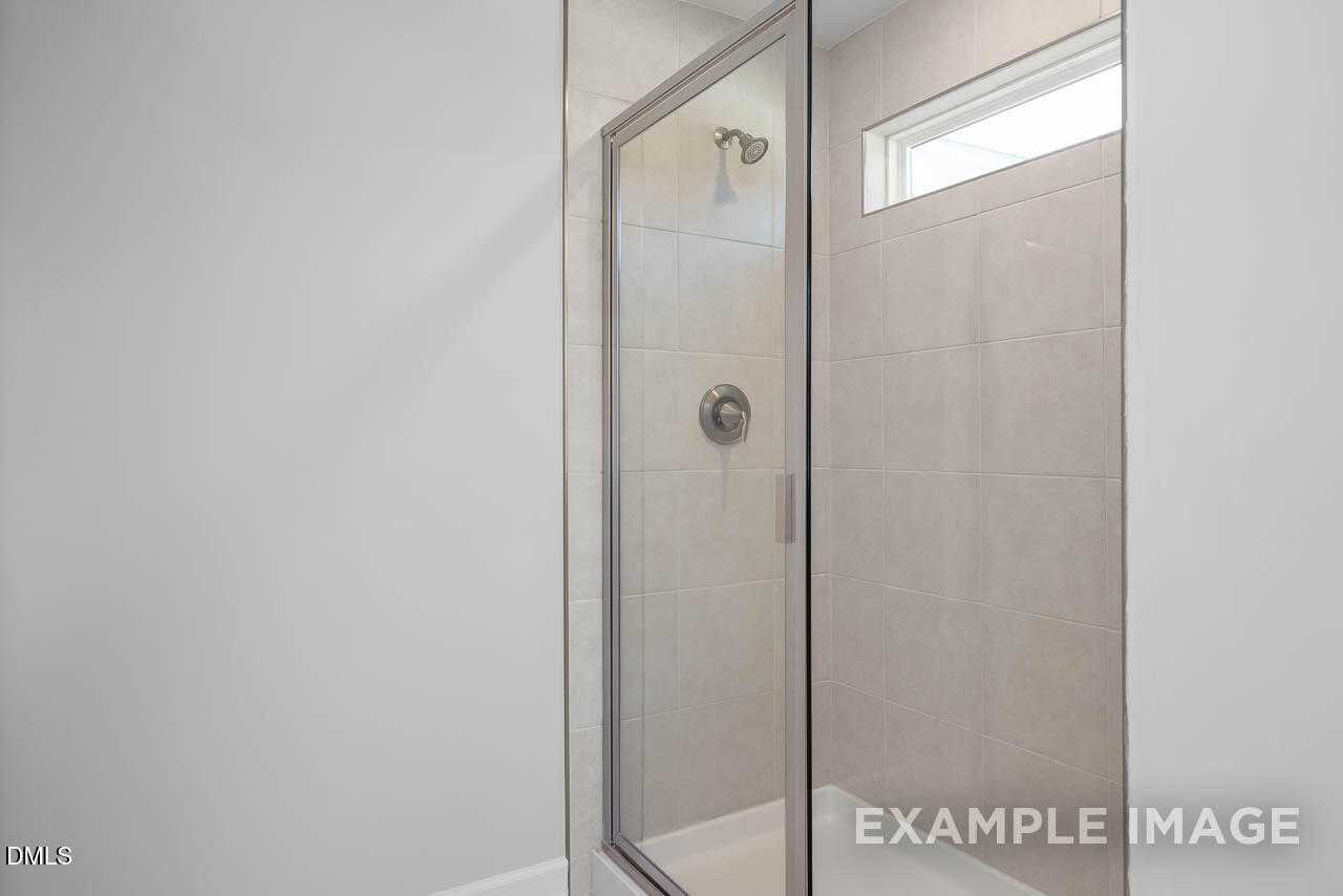 Modern glass shower enclosure with white subway tiles and clerestory window in master bath of Davidson Homes The Adalynn A in Lillington, NC