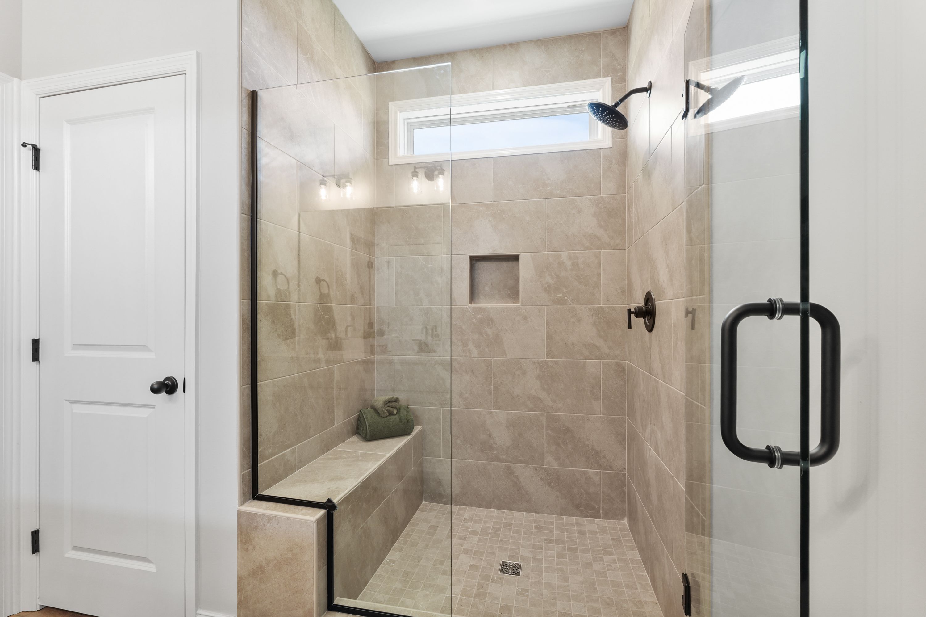Spacious walk-in shower with glass enclosure at Ramsay Cove in Owens Cross Roads, Alabama featuring tiled bench and rain showerhead