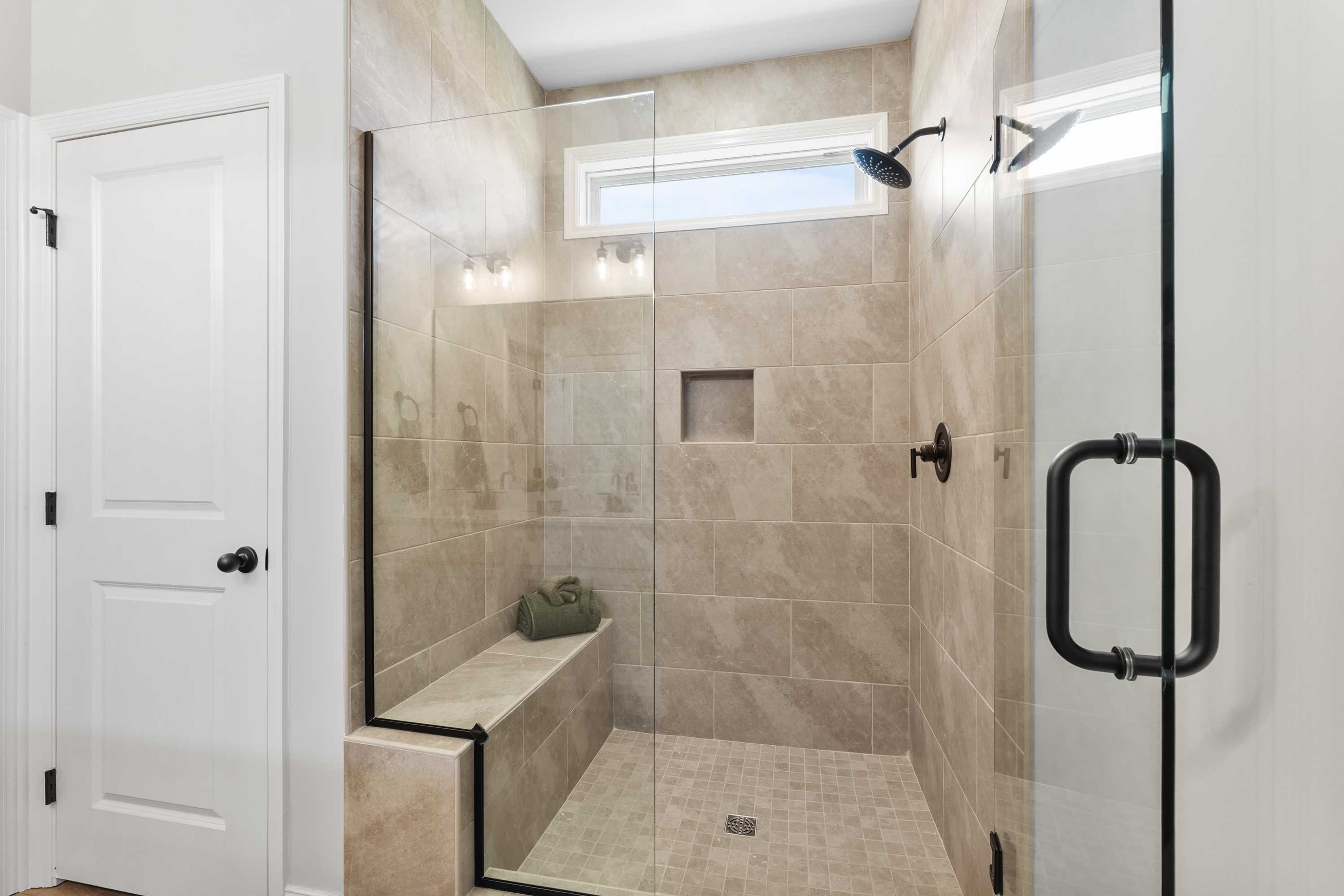 Spacious walk-in shower with glass enclosure at Ramsay Cove in Owens Cross Roads, Alabama featuring tiled bench and rain showerhead