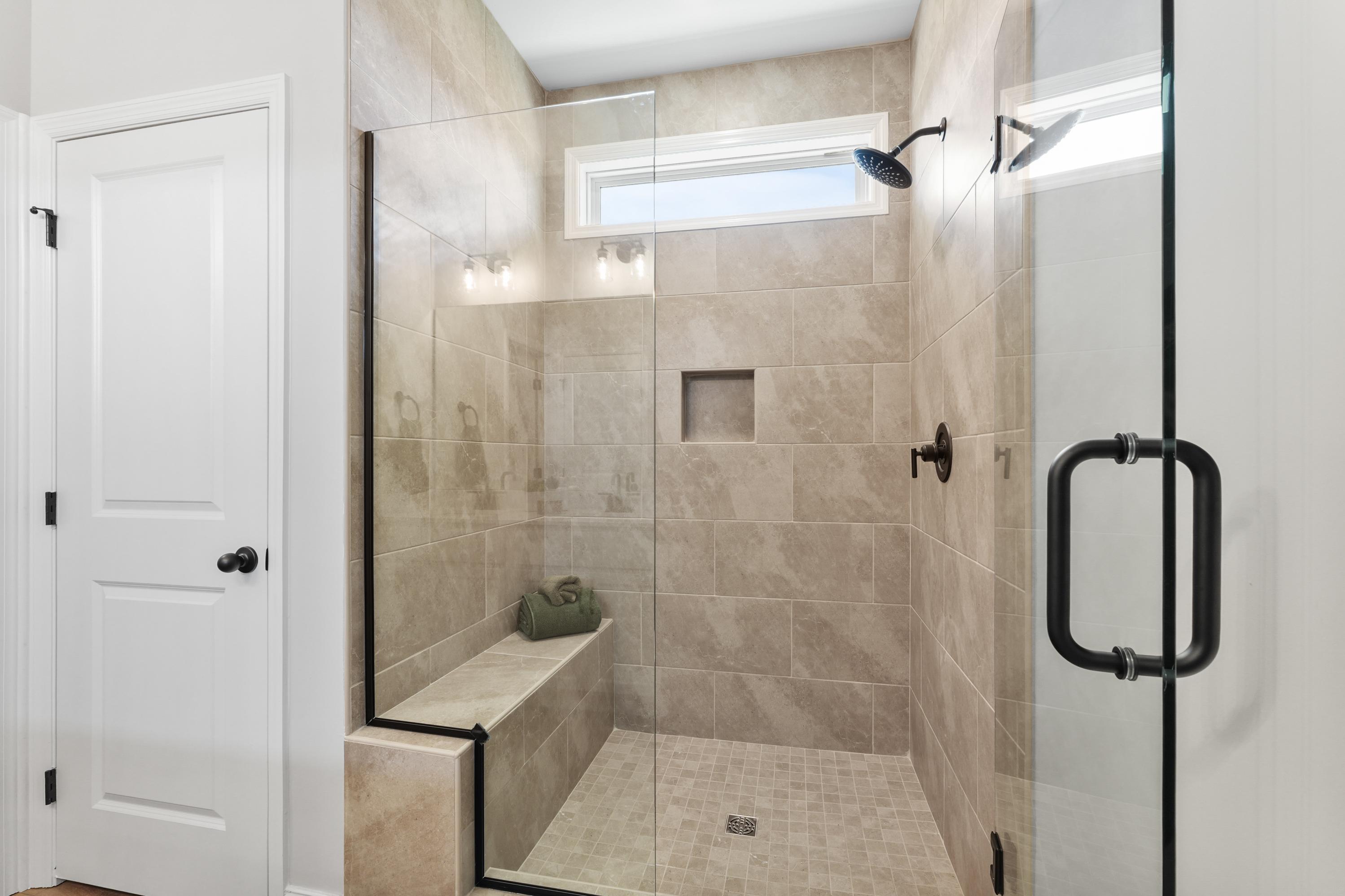 Spacious walk-in shower with glass enclosure at Ramsay Cove in Owens Cross Roads, Alabama featuring tiled bench and rain showerhead
