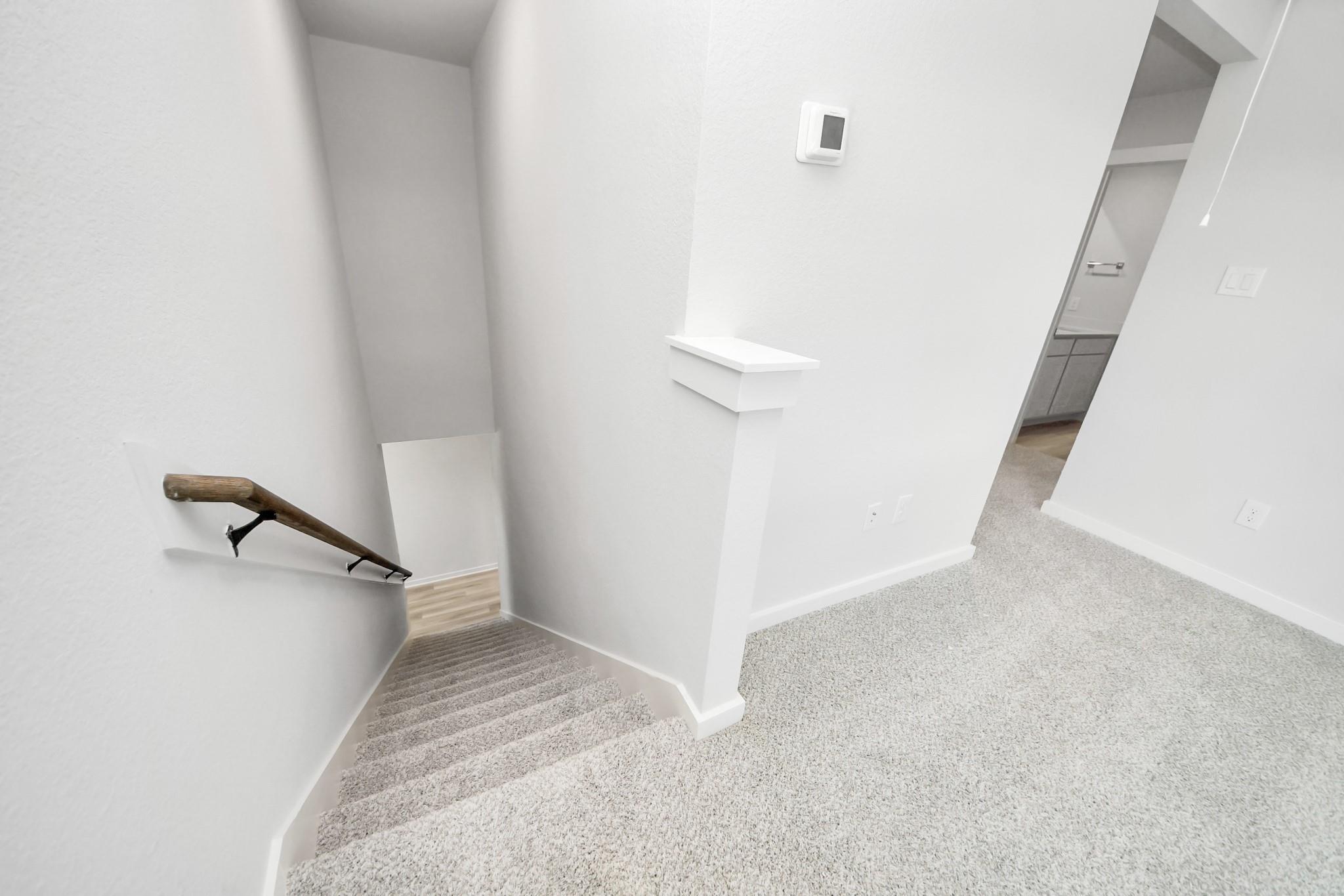 Carpeted staircase with wooden handrail in The Sabine F floor plan by Davidson Homes in Liberty Estates, Cleveland, Texas.