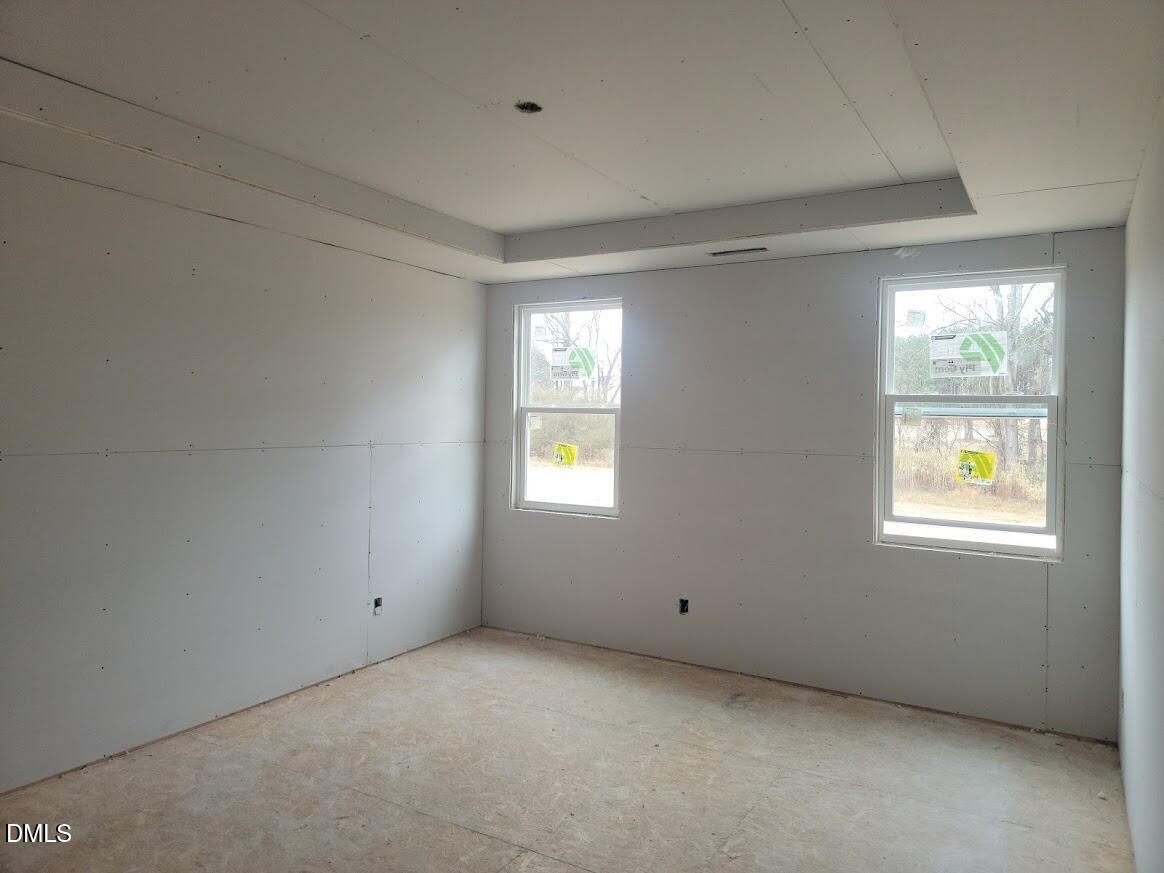 Unfinished secondary bedroom with drywall walls, two double-hung windows, and subfloor in 5-bedroom Davidson Homes The Ashport G, Angier, NC