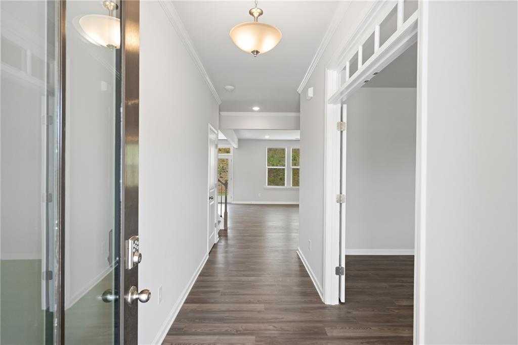 Bright entry hallway with hardwood floors, glass front door, and chandelier in Davidson Homes The Hickory B, Winder, Georgia