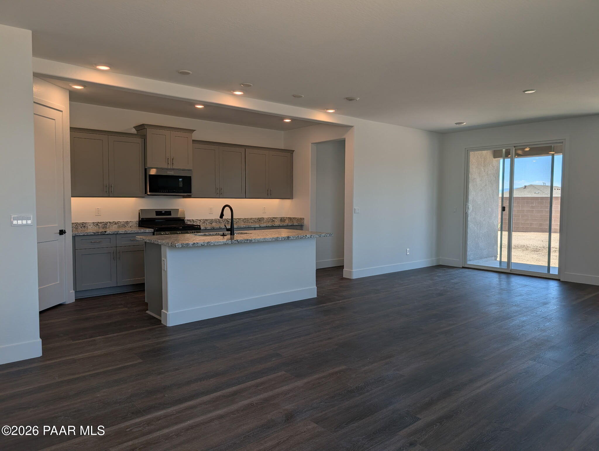 Open-concept kitchen with island, gray cabinets, and granite countertops in The Frontier II F at South Ranch, Prescott.