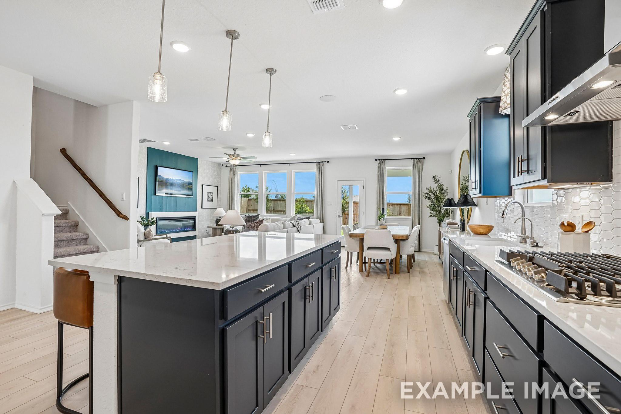 Open-concept kitchen with navy island, quartz countertops, and gas cooktop in Davidson Homes Ashport J, Crosby, Texas