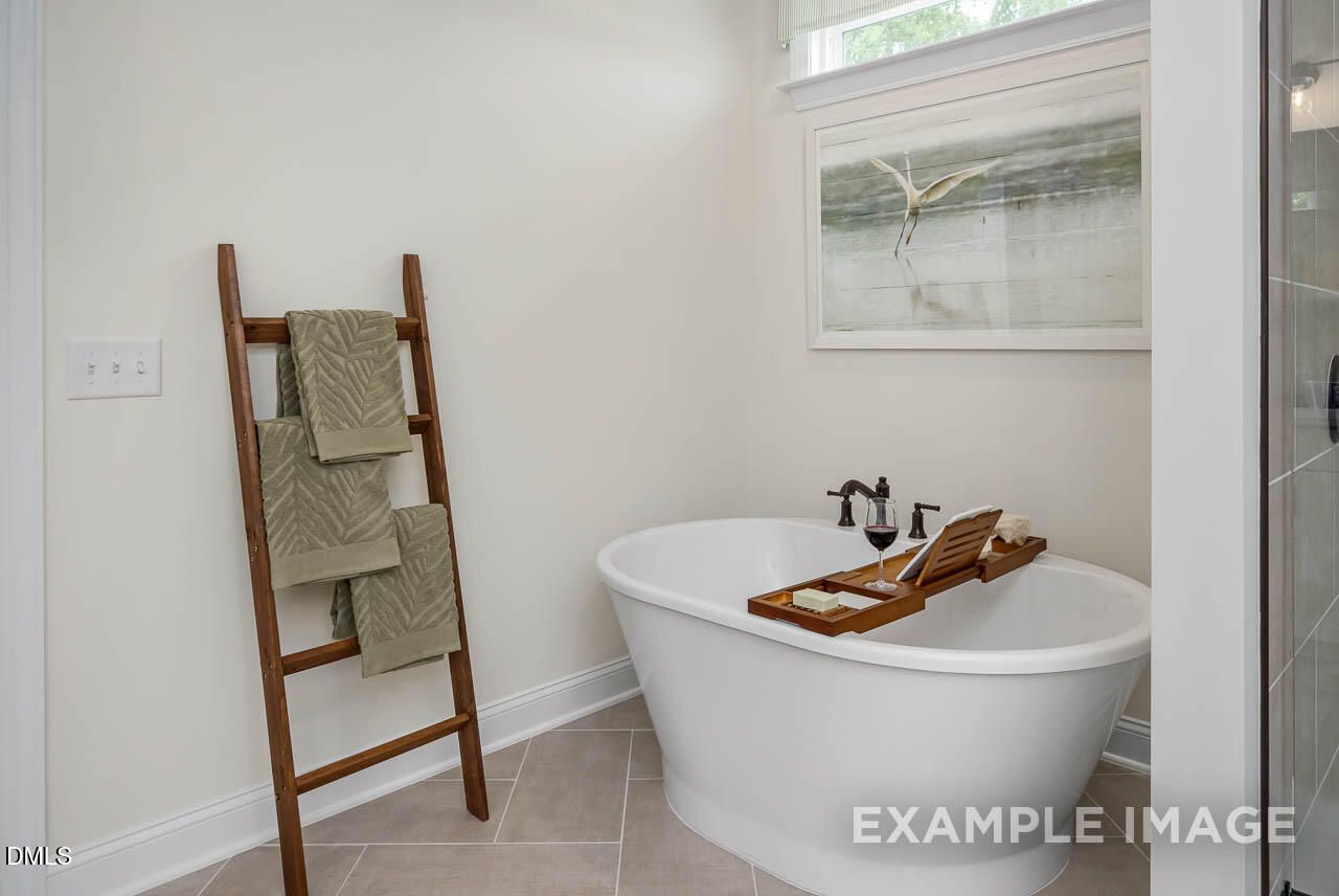 Luxurious master bathroom featuring freestanding tub, wooden towel ladder, and serene artwork in Davidson Homes The Crawford D, Angier, NC