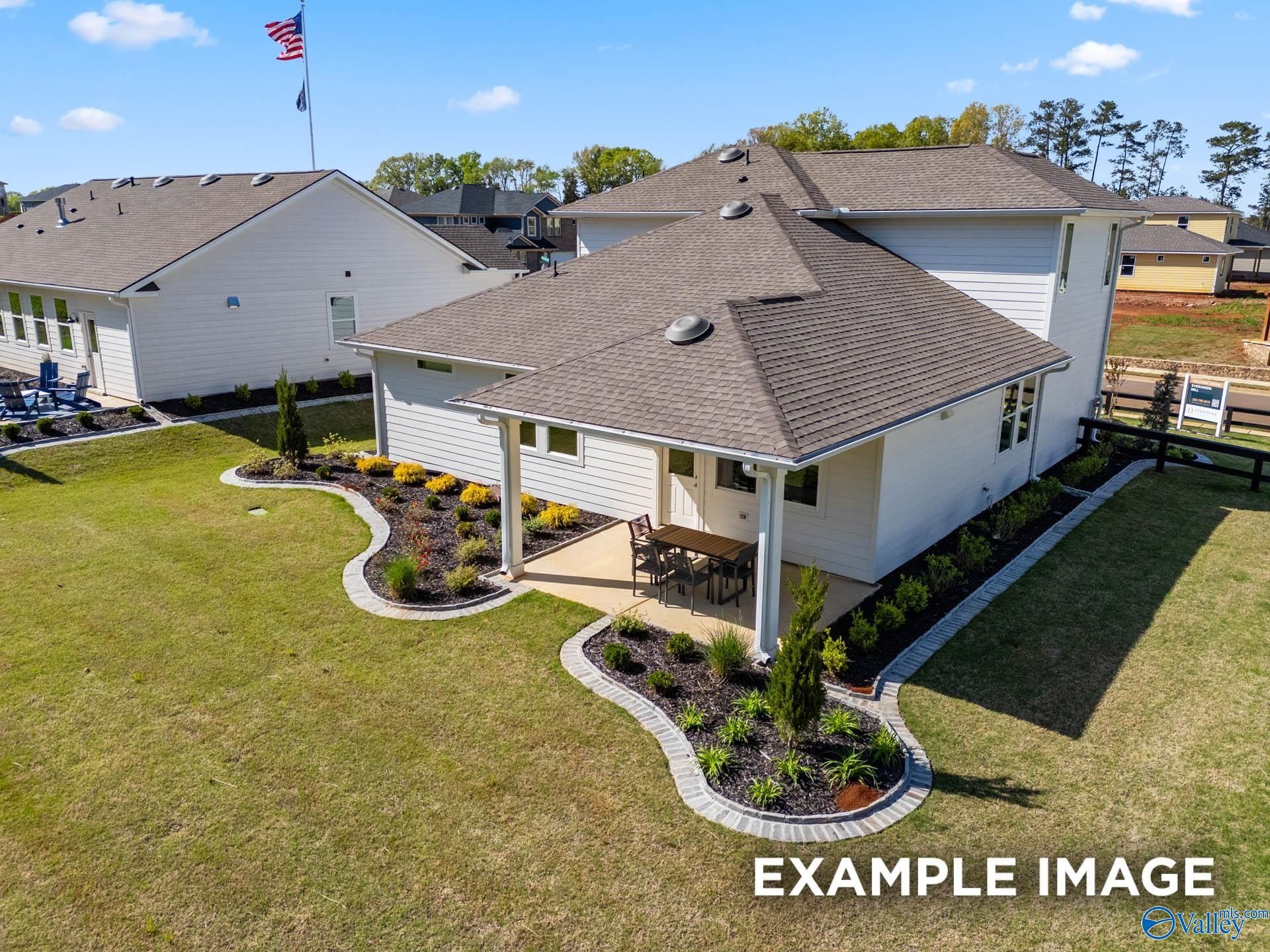 Two-story white Davidson Homes The Stella with covered back patio, curved landscaped beds, and green yard in Evergreen Mill, Madison, Alabama