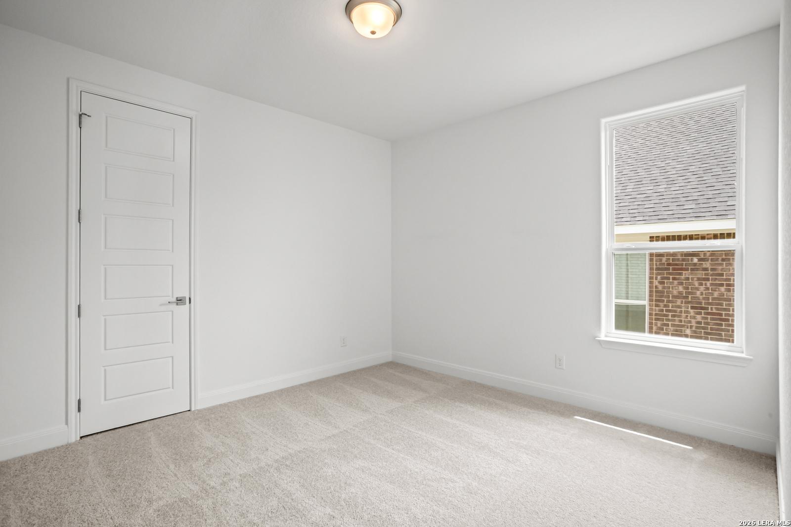 Bright, carpeted secondary bedroom in The Lanier G floor plan at The Reserve at Potranco Oaks in Castroville, Texas.