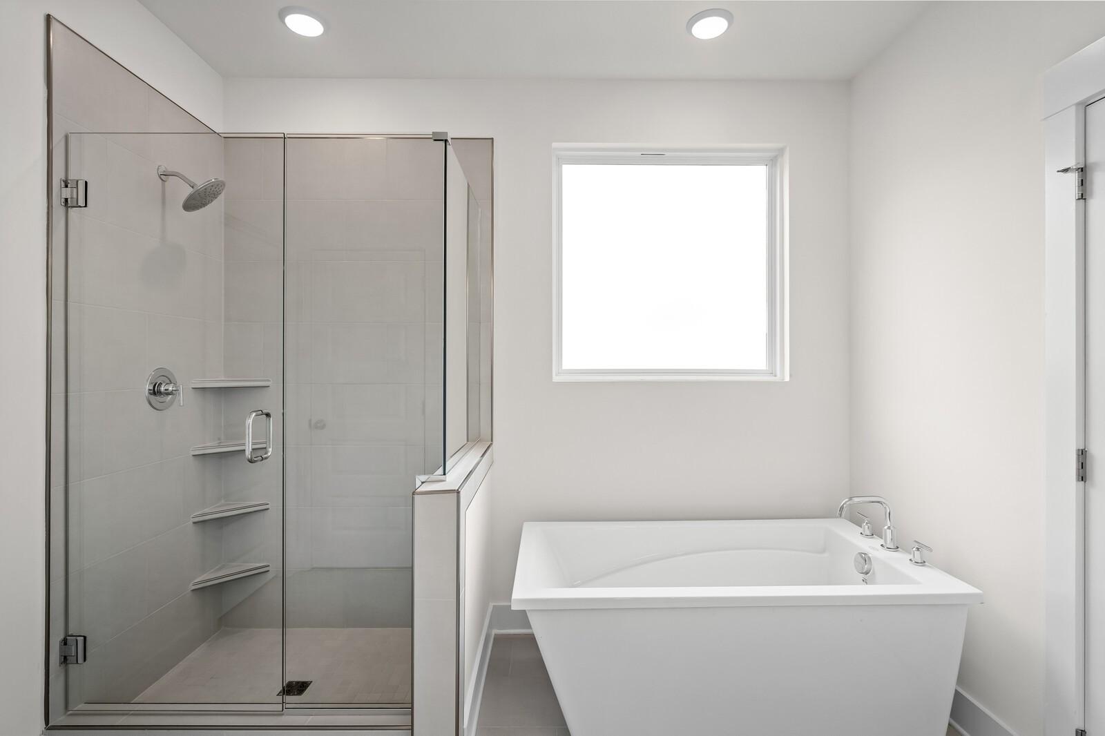 Modern master bathroom with glass walk-in shower and freestanding soaking tub in Davidson Homes The Ridgeport, Gallatin, Tennessee