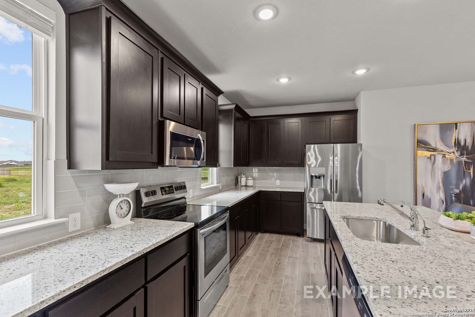 Modern kitchen with dark cabinets, granite counters, stainless appliances in 3-bed Davidson Homes Collin A, Seguin, TX